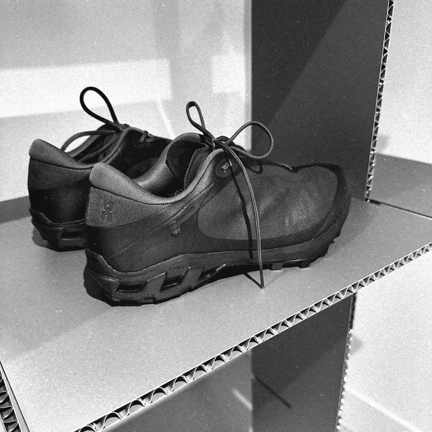 Black athletic sneakers on cardboard shelves in a minimalist display setting