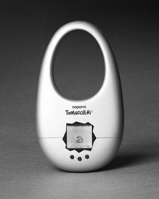 White Coperni Tamagotchi virtual pet device with screen and three buttons on gray background