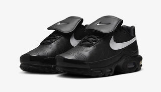 Black Nike Air Max Plus Tiempo sneakers with white swoosh and flap detail on white background