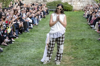 Model wearing white sleeveless top and plaid pants with lace patches on outdoor fashion runway