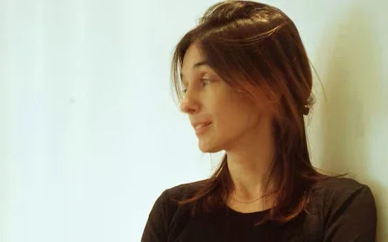 Profile of a woman with medium brown hair wearing a black shirt against a light background