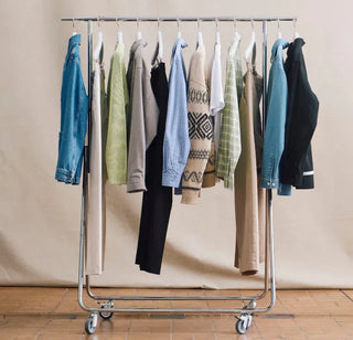 Clothing rack with diverse casual jackets, sweaters, shirts, and pants in neutral and blue tones