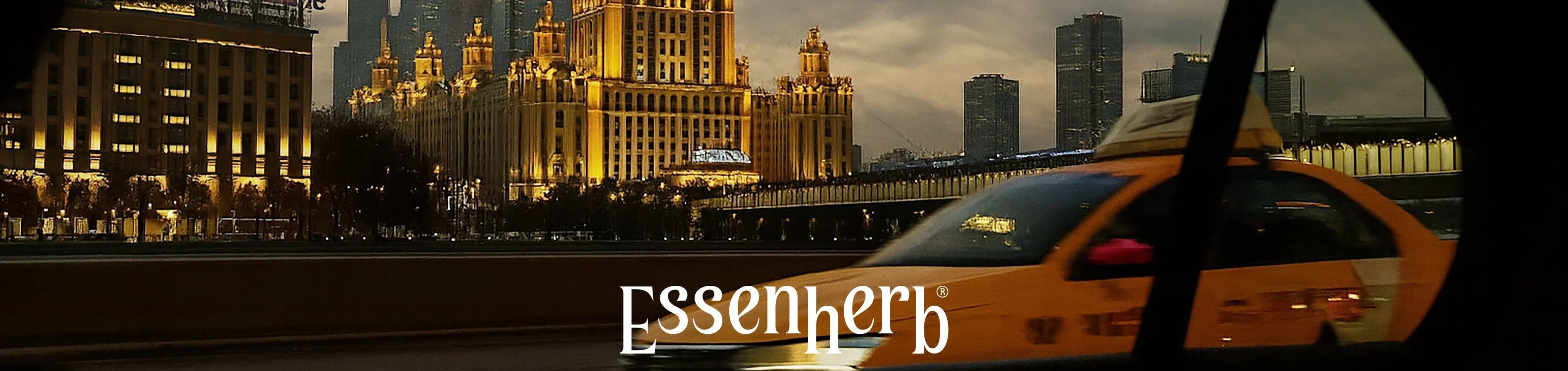 Yellow taxi driving on city street with illuminated historic building and modern skyscrapers at dusk