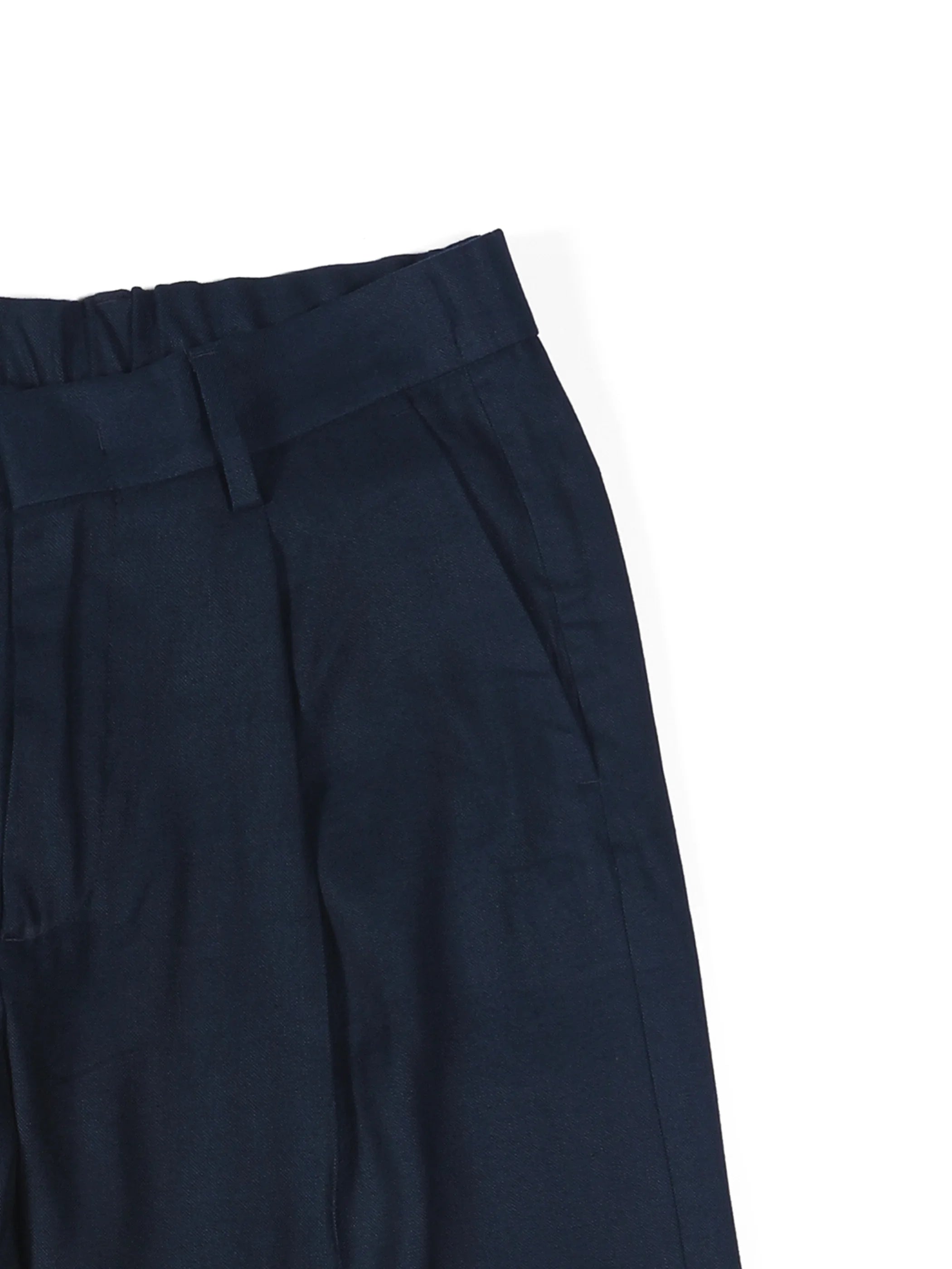 Close-up of navy blue tailored trousers with belt loops and side pockets on white background