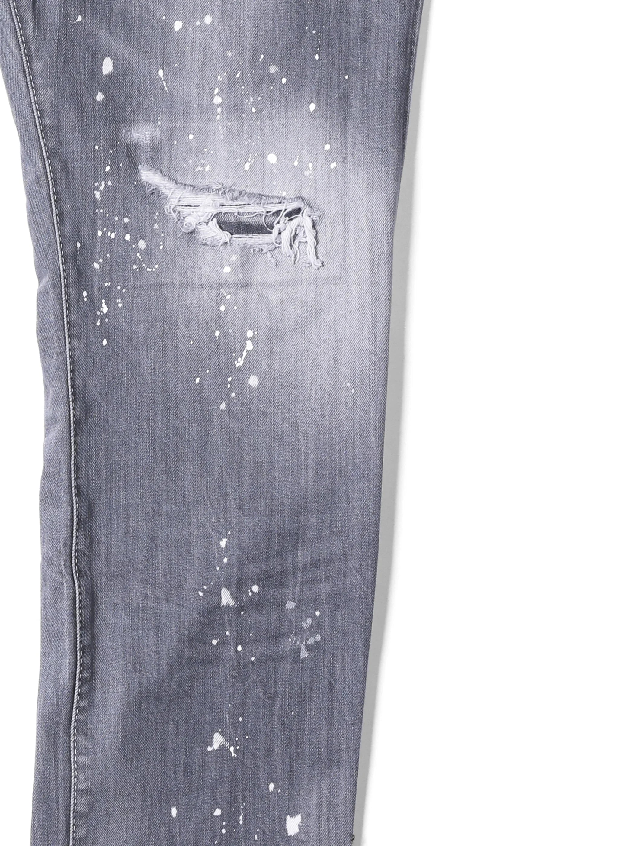 Gray distressed denim jeans leg with ripped hole and white paint splatter details