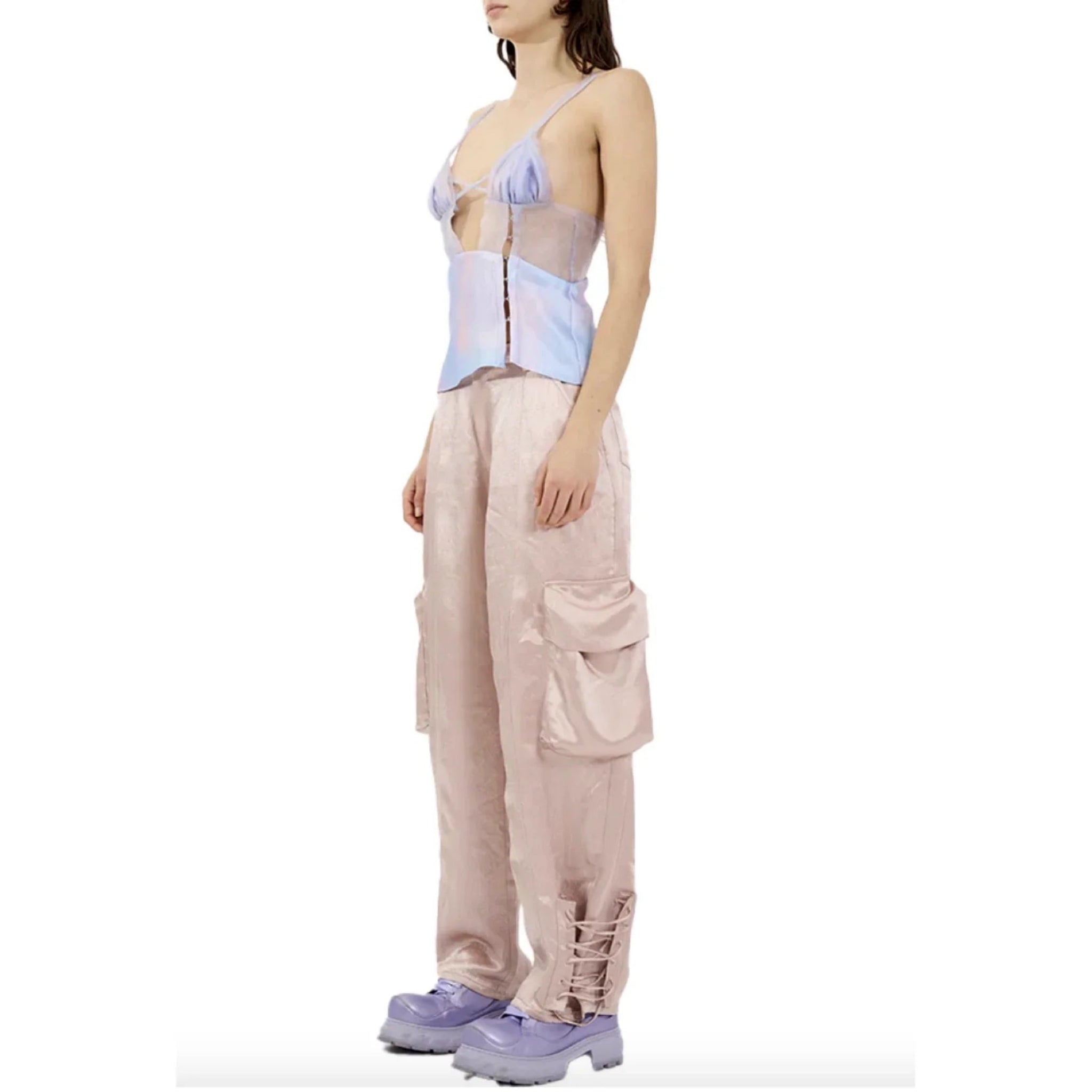 Female model wearing light pink satin cargo pants with side pockets and lavender platform shoes