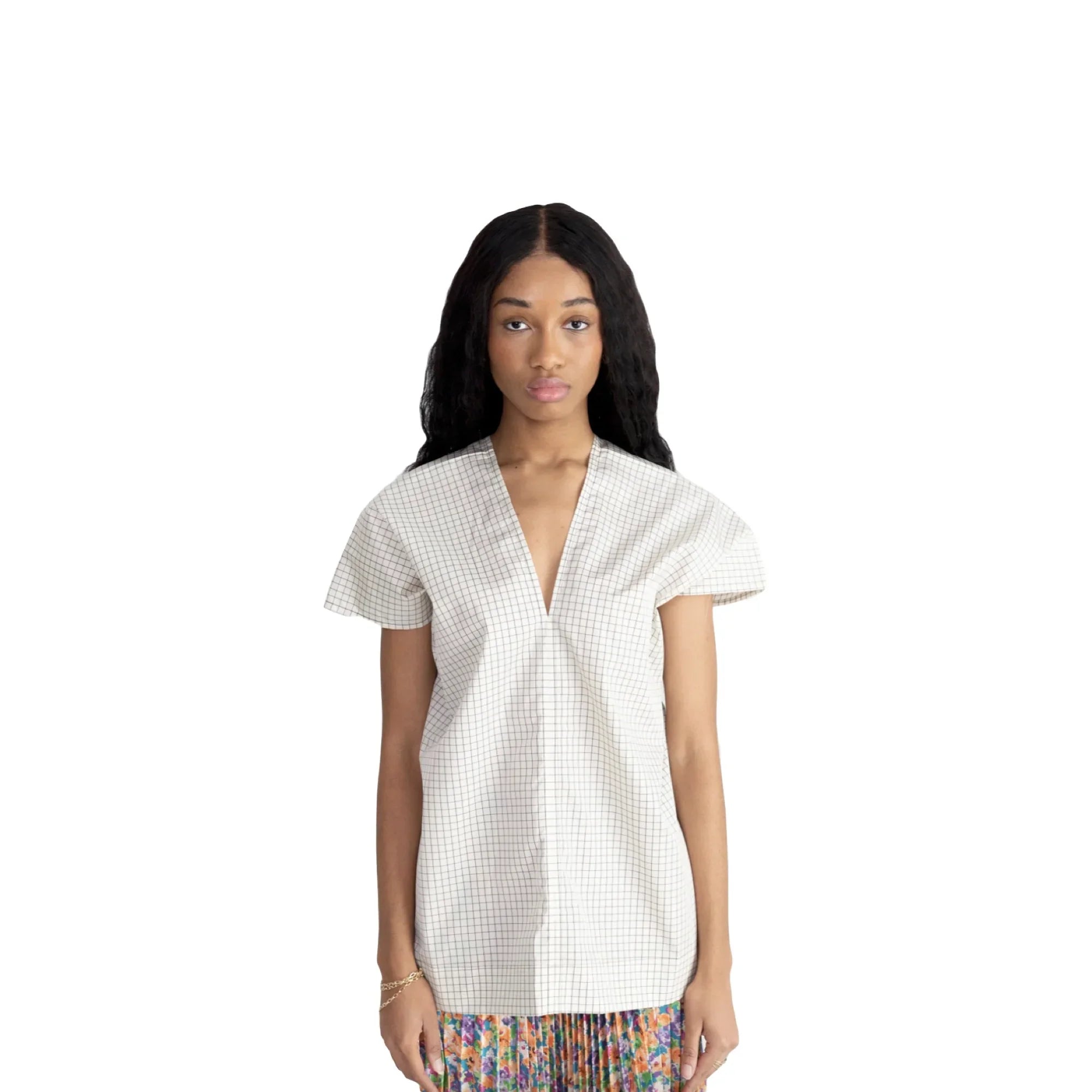 Young woman wearing a white short-sleeve checkered top with a deep V-neck and a colorful floral skirt