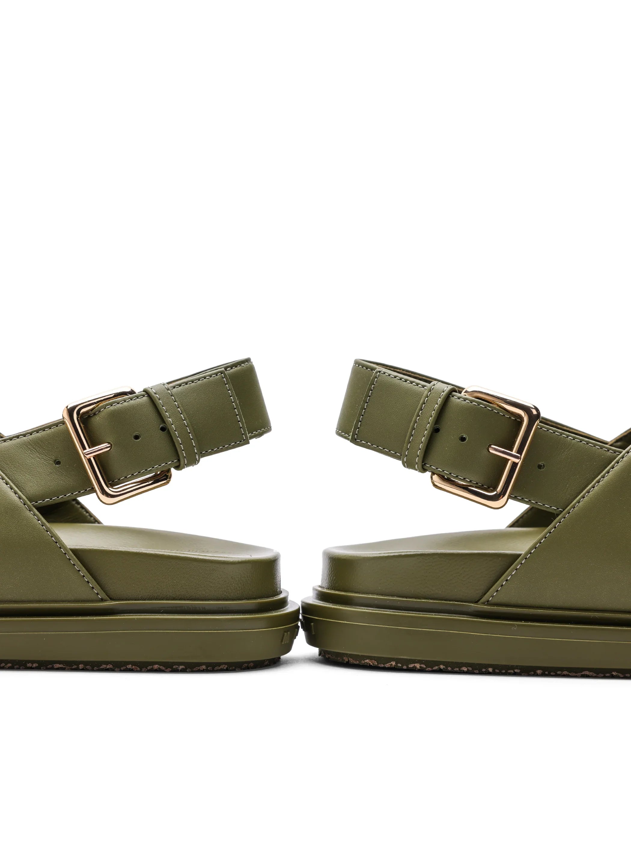 Close-up of olive green sandals with gold buckles on white background