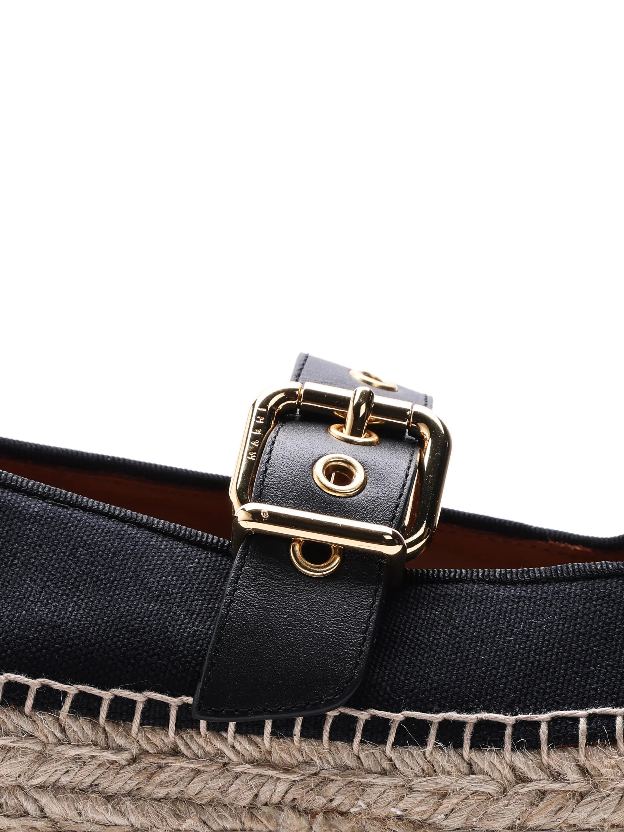 Close-up of black canvas espadrille shoe with gold buckle and woven jute sole