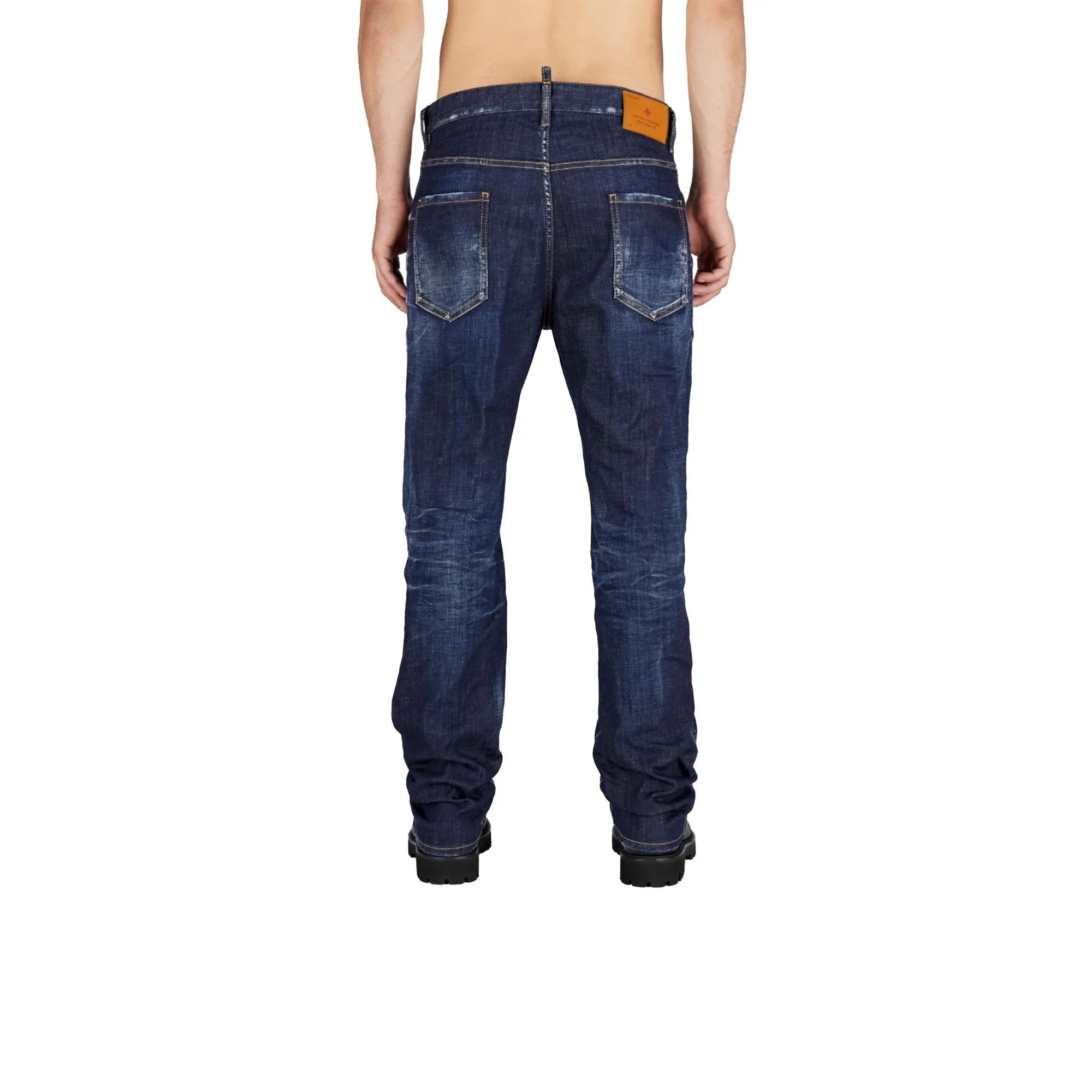 Back view of a person wearing dark blue faded denim jeans and black boots on white background