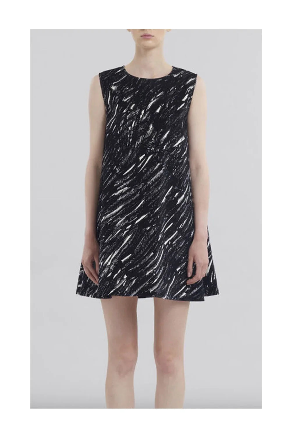 Woman wearing sleeveless black and white abstract print mini dress on gray background