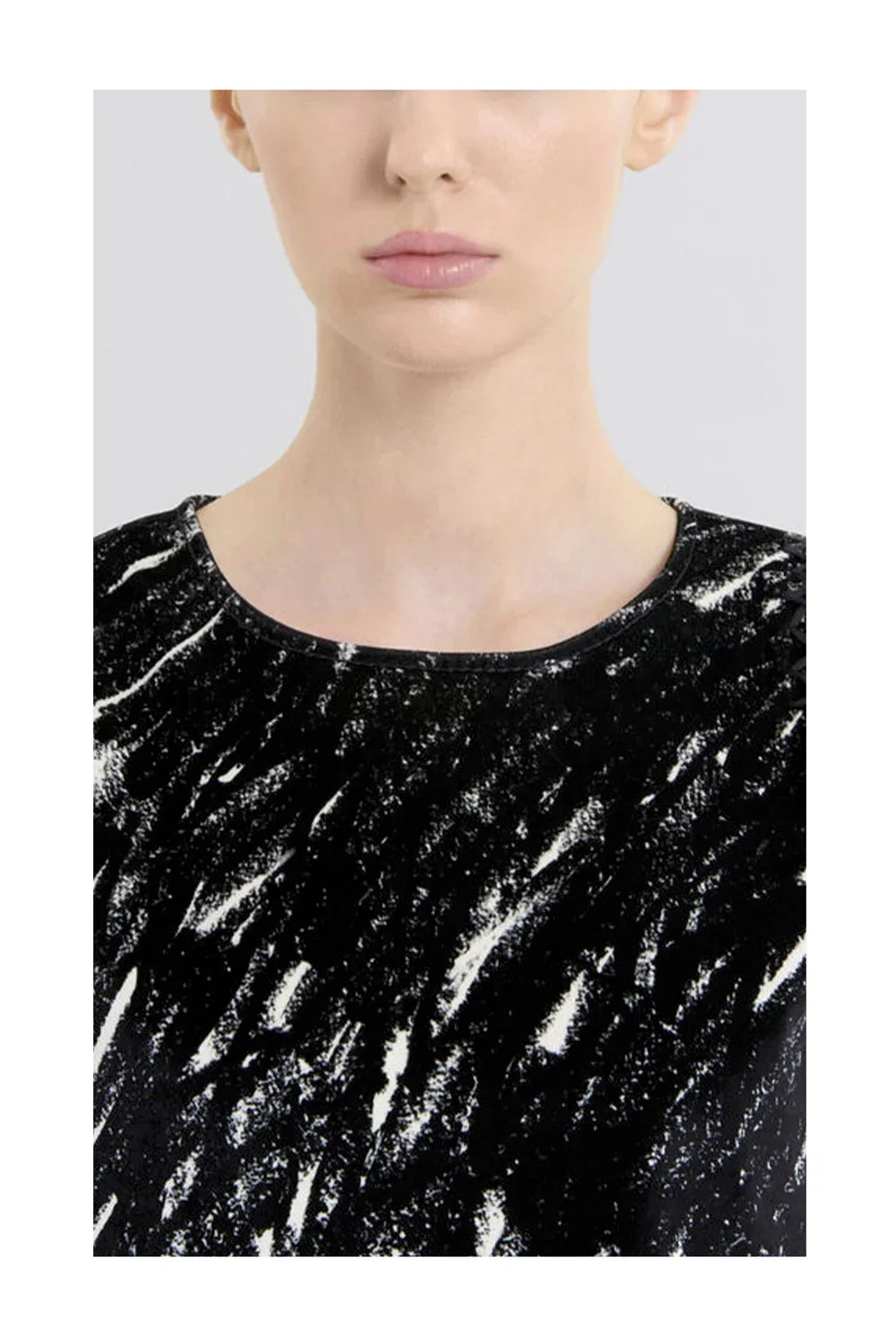 Close-up of a woman's neck and lips wearing a black and white abstract patterned top