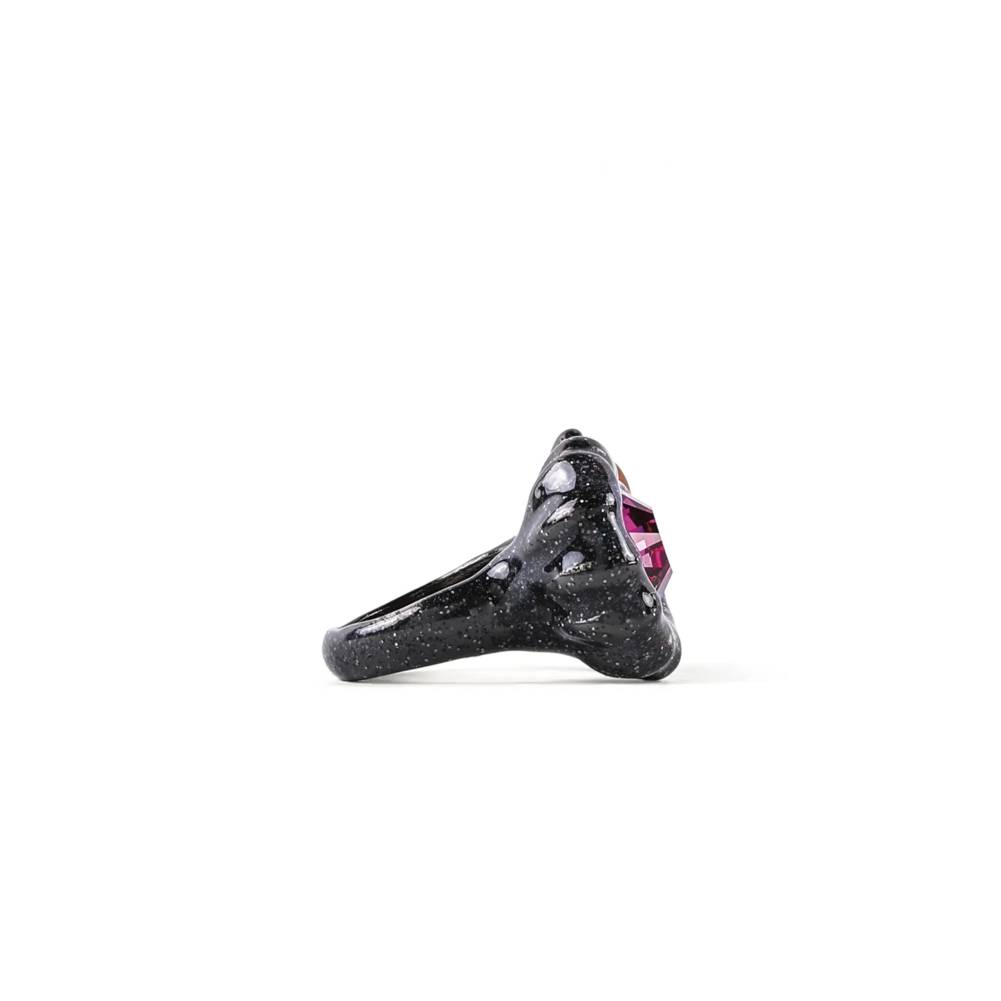 Black speckled resin ring with a large faceted purple gemstone on white background