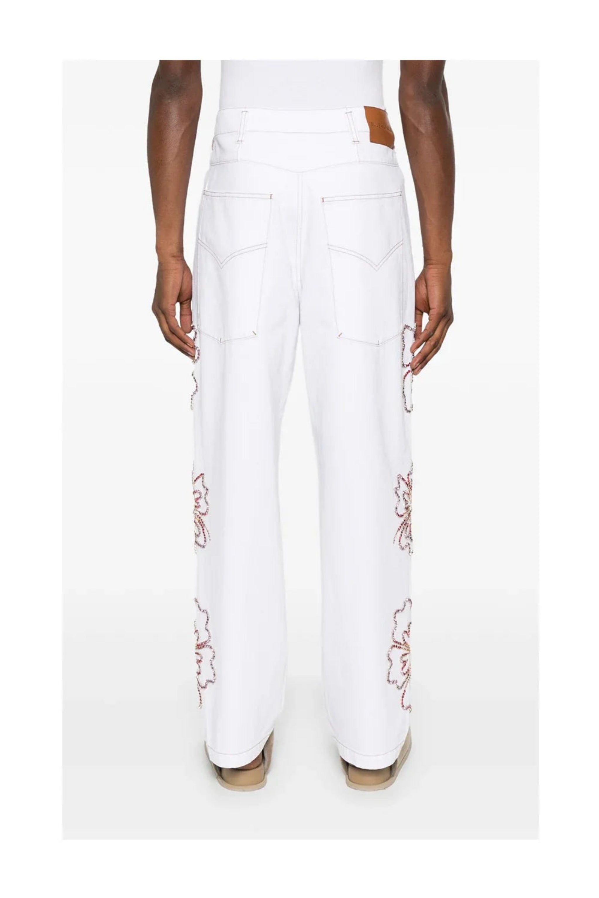Back view of person wearing white straight-leg jeans with embroidered floral details on sides
