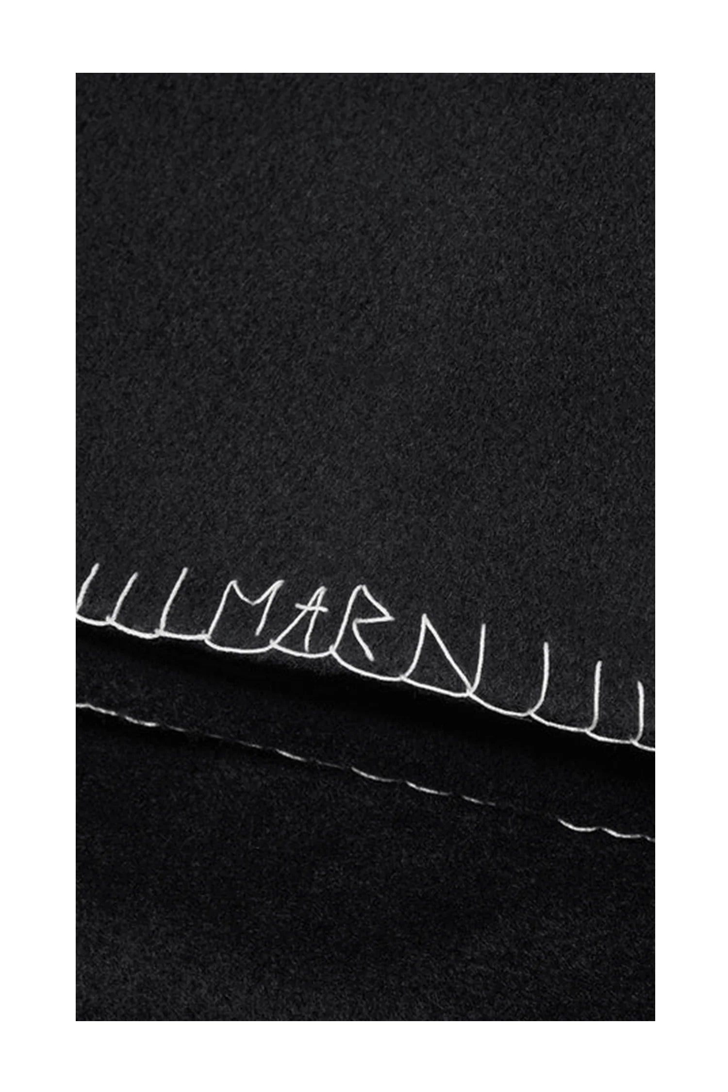 Black wool fabric with white blanket stitch detailing and visible embroidered letters