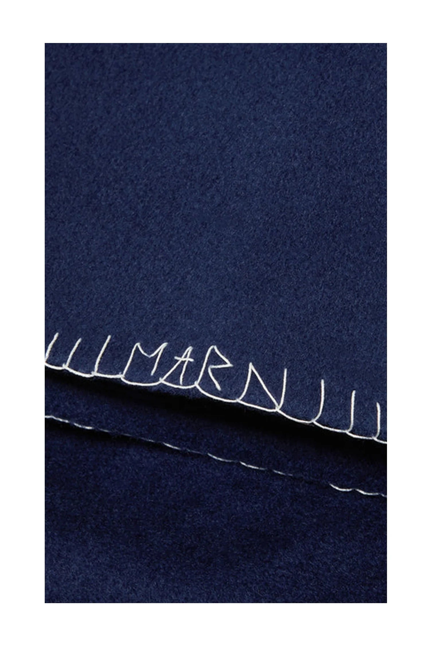 Close-up of navy blue wool fabric with white hand-stitched hem detail and letters