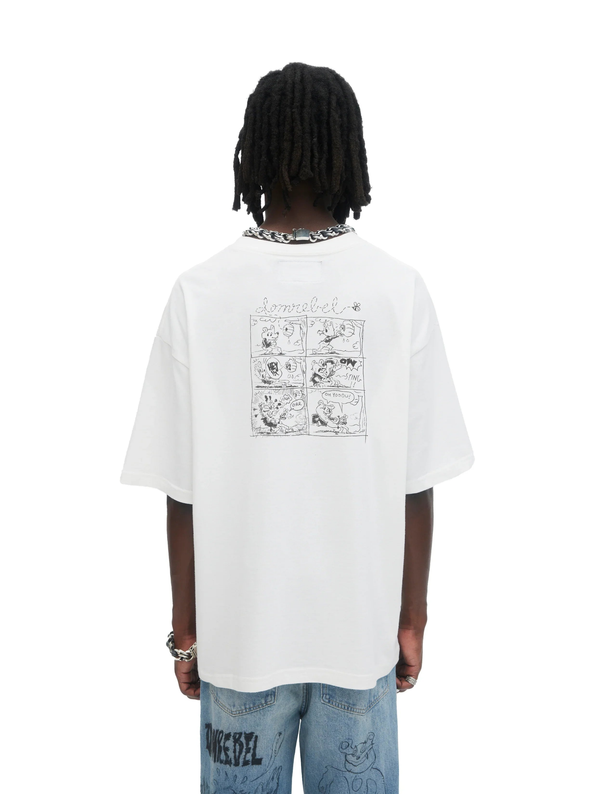 Back view of person wearing white Domrebel T-shirt with black comic strip graphic and light blue jeans with cartoon designs
