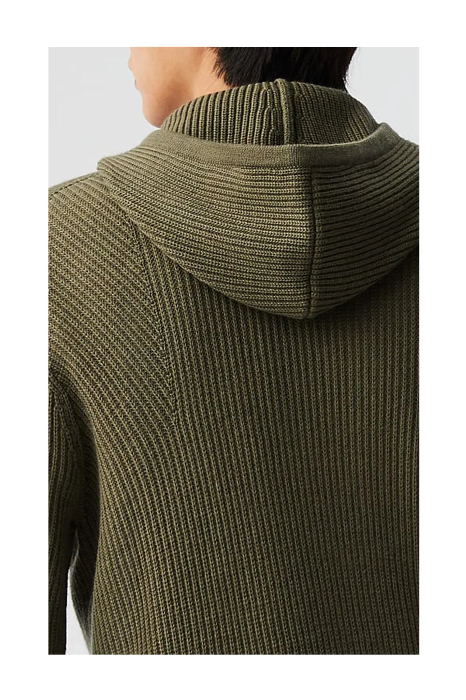 Close-up of a person wearing an olive green ribbed knit hoodie sweater from the back