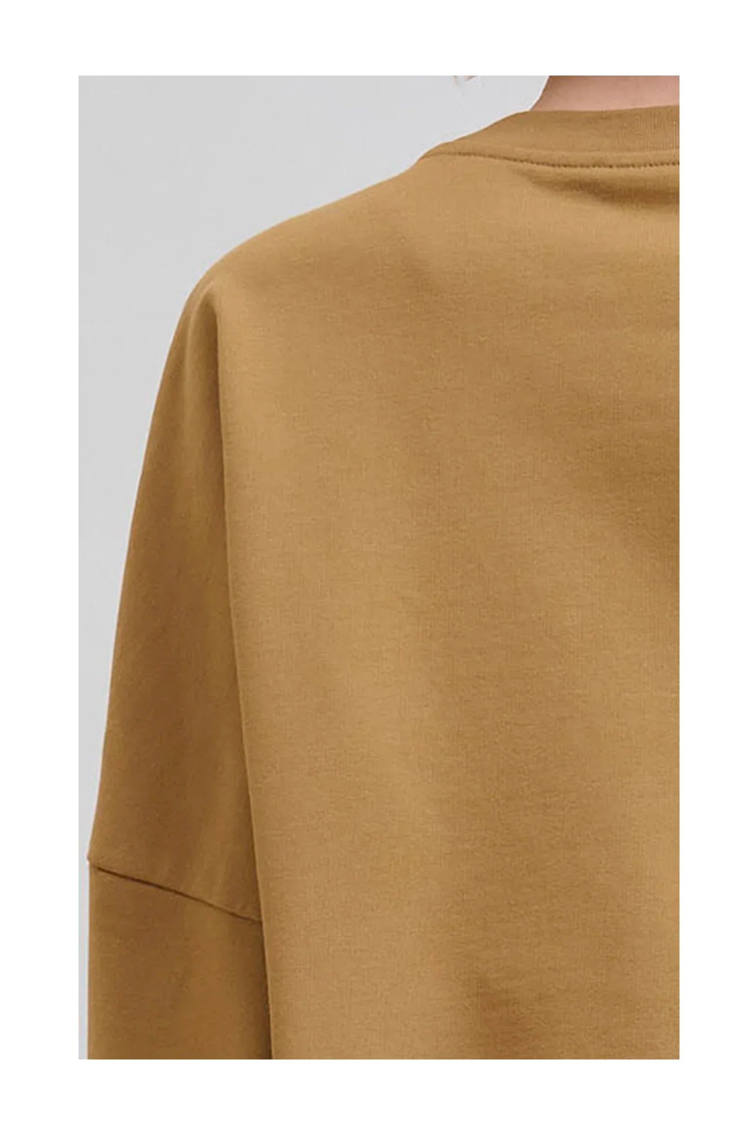 Close-up of camel brown sweatshirt fabric showing shoulder seam and collar detail