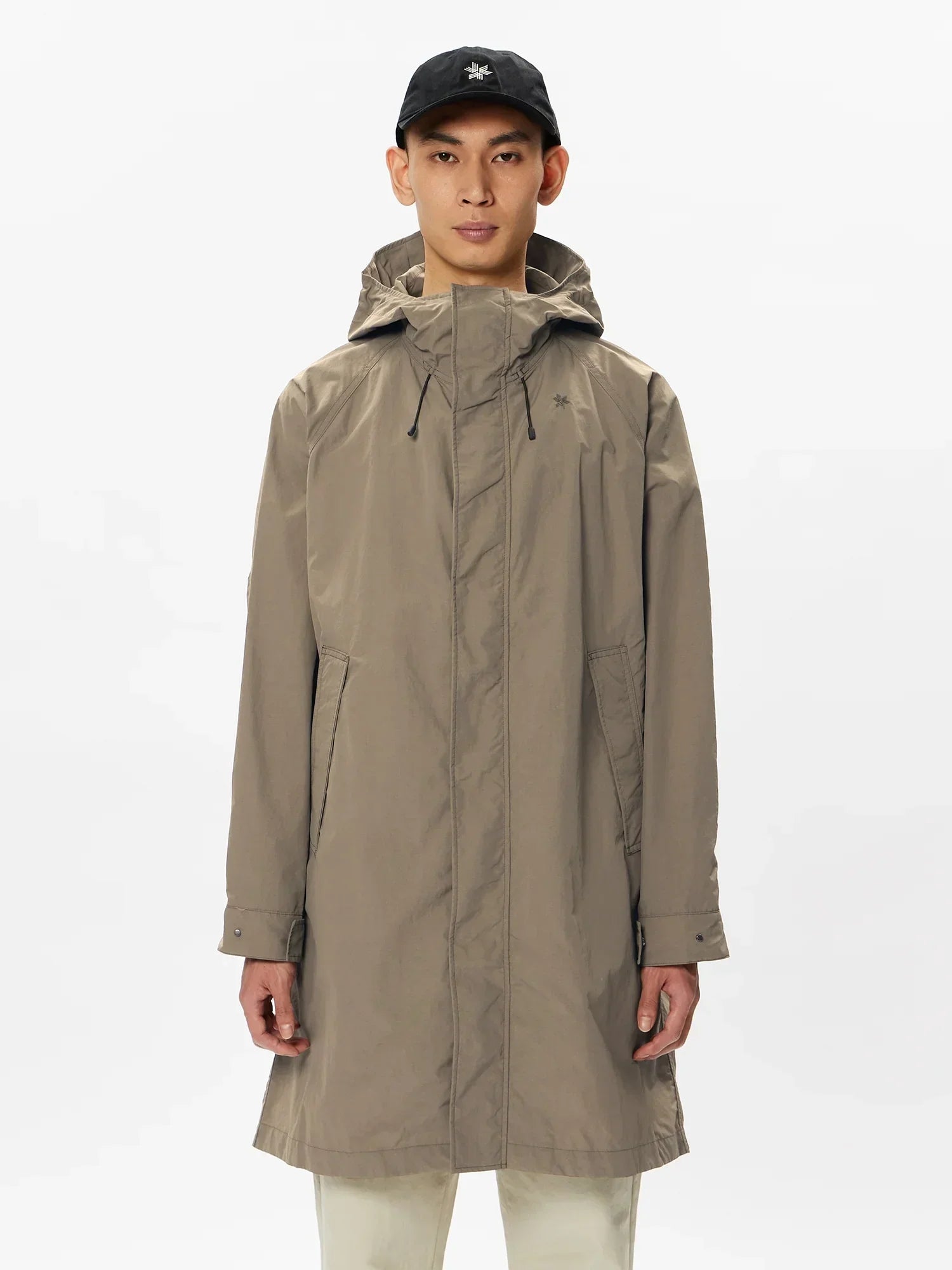Man wearing taupe hooded waterproof parka jacket with front pockets and black cap
