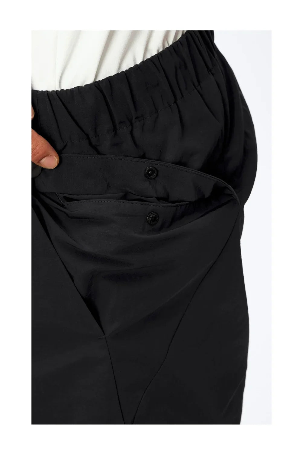 Close-up of hand pulling open buttoned black elastic waistband pants pocket