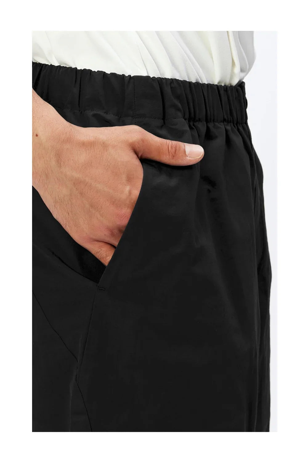 Close-up of hand in pocket of black elastic waist pants with white shirt