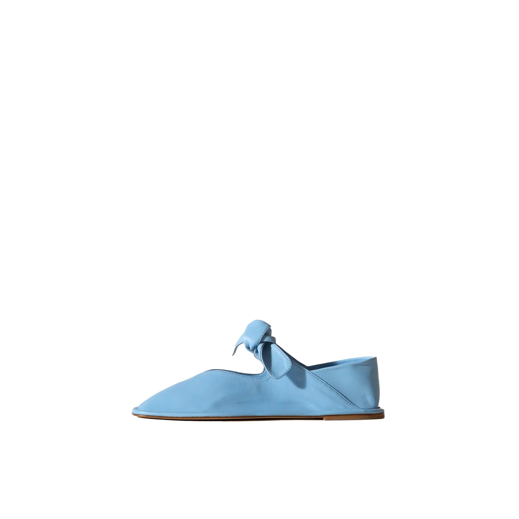 Light blue leather flat shoe with bow detail and brown sole on white background