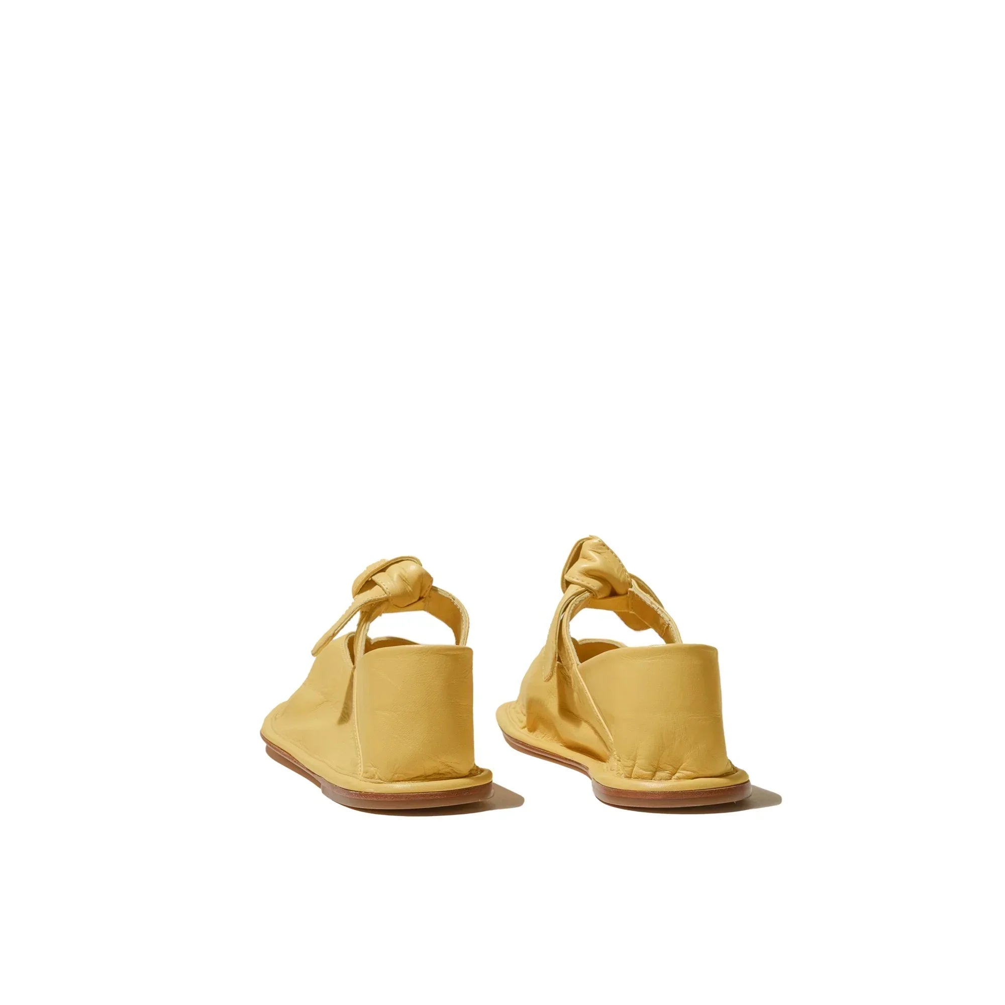 Yellow leather slingback shoes with wooden soles shown from the back on white background