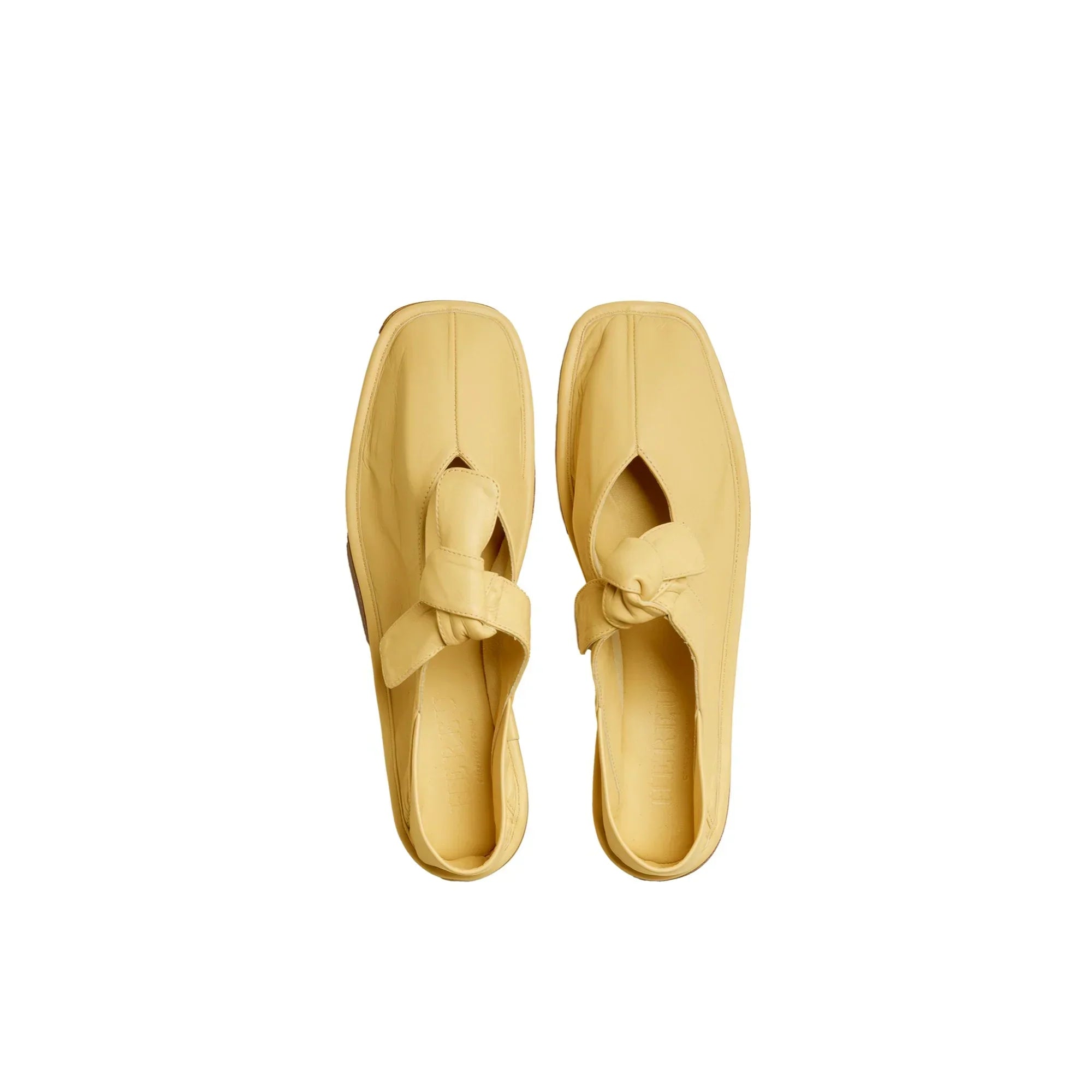 Yellow leather slip-on shoes with a front knot detail on white background