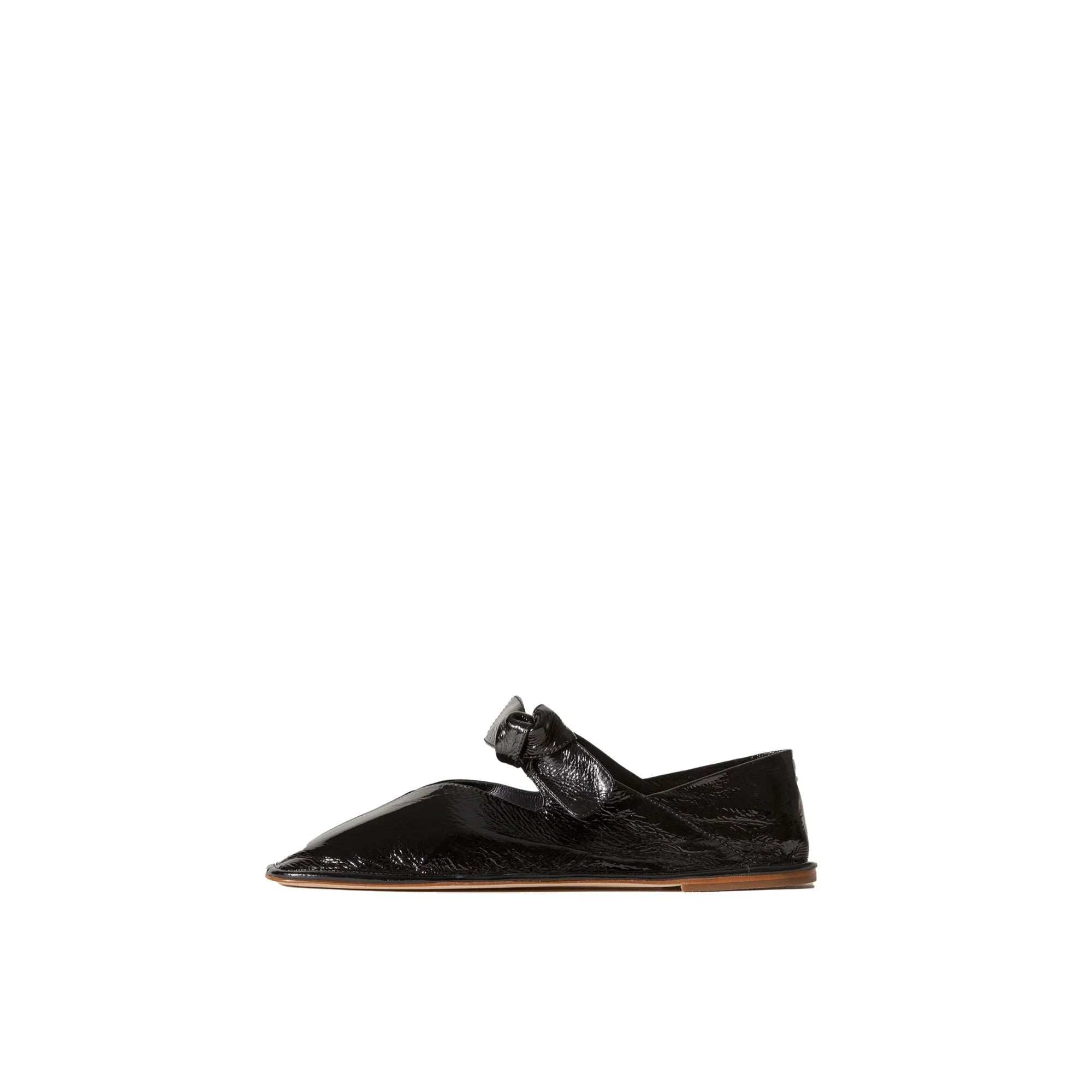 Black crinkled glossy pointed toe flat shoe with a knotted strap and tan sole