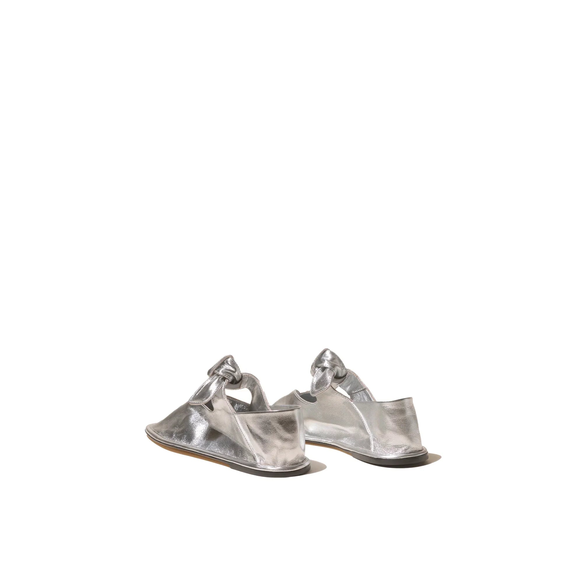 Pair of metallic silver leather slip-on shoes with knot detail on white background