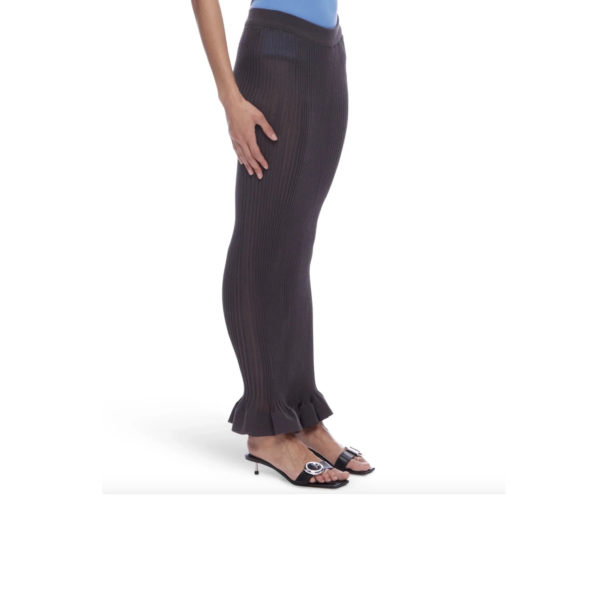 Side view of a person wearing black ribbed knit pants with ruffled hems and black heeled sandals