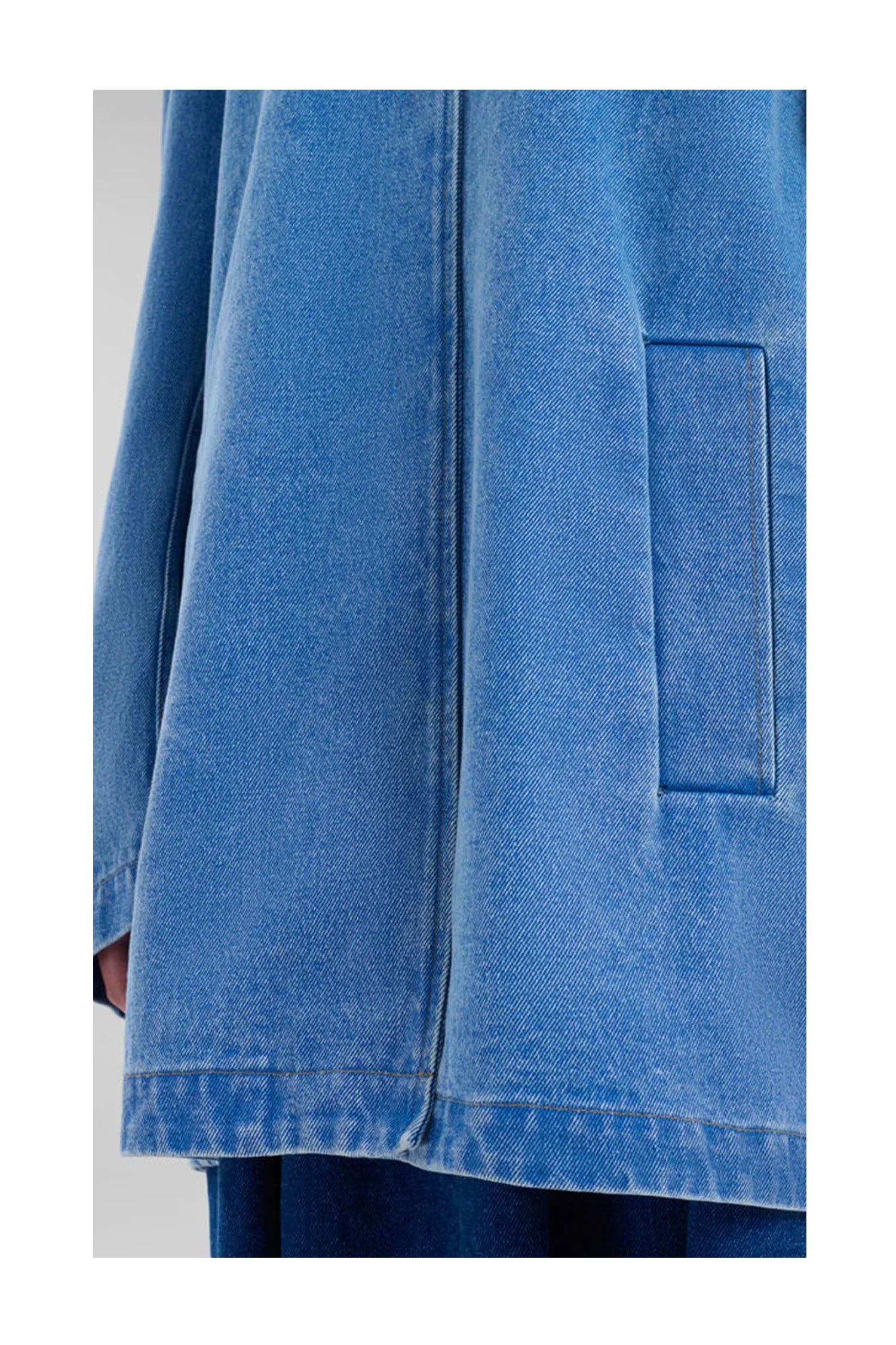 Close-up of light blue denim jacket pocket and seam detail on a casual outerwear jacket
