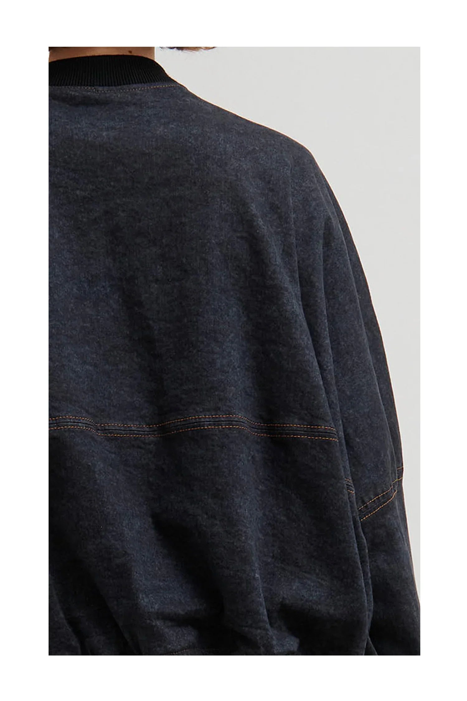 Close-up of dark gray garment with orange stitching details and ribbed collar