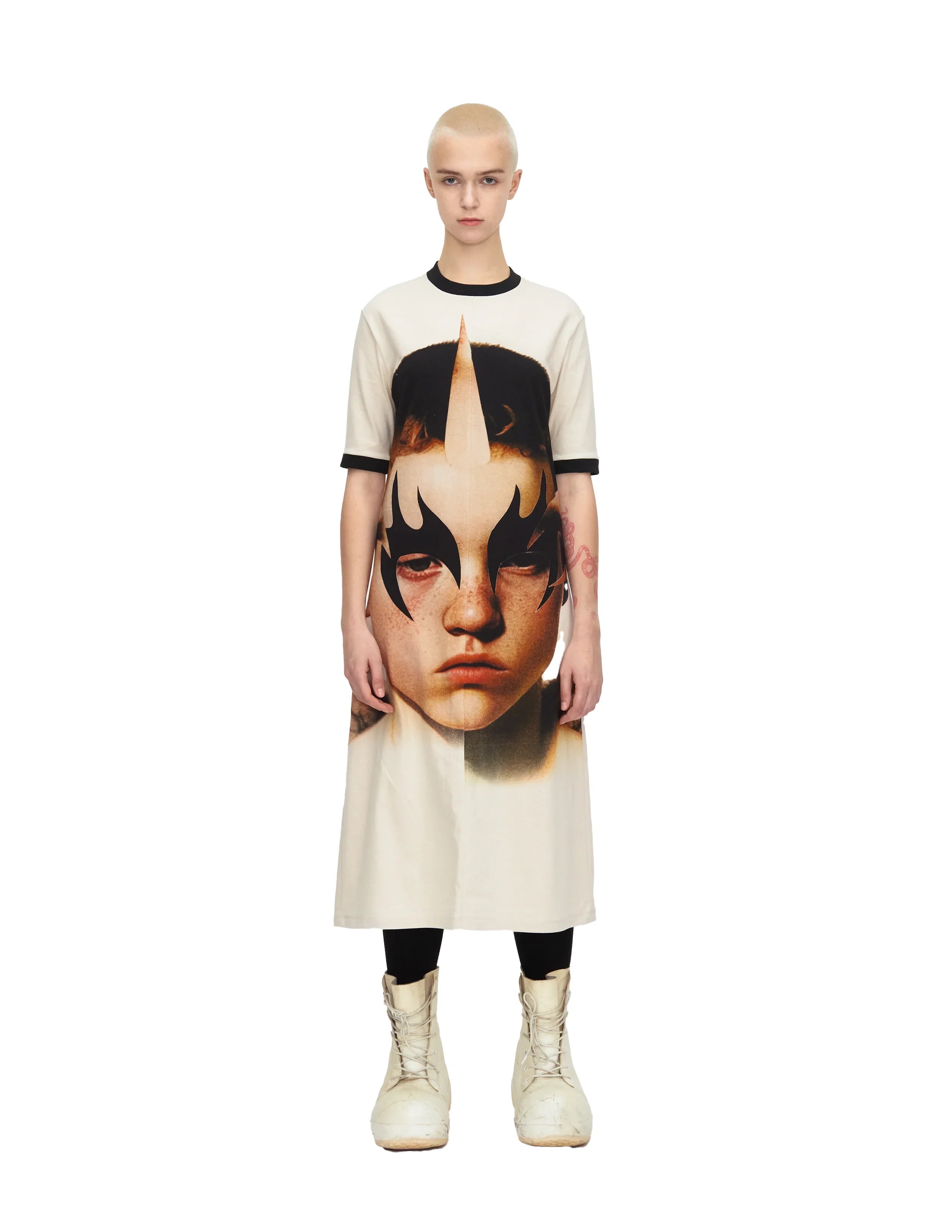 Model wearing midi dress with large face print and black eye makeup design, white boots
