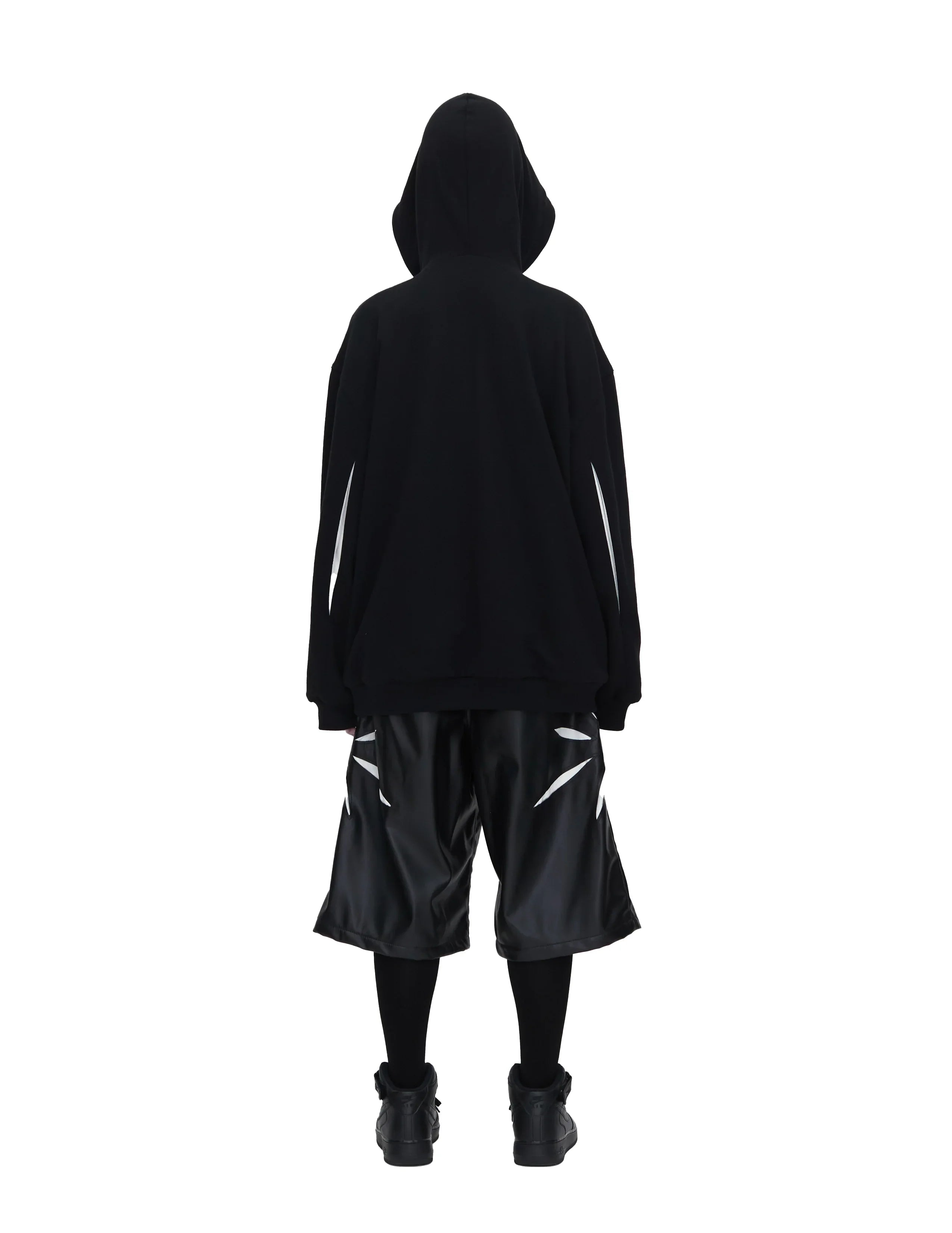 Rear view of person wearing black oversized hoodie and shiny black shorts with white abstract stripes