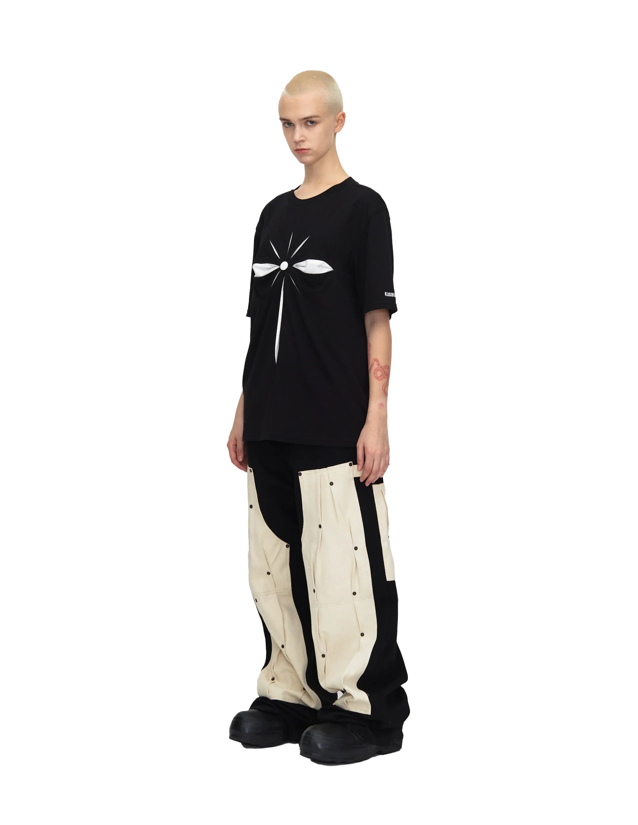 Model wearing black oversized t-shirt with white abstract origami design and black and beige cargo pants