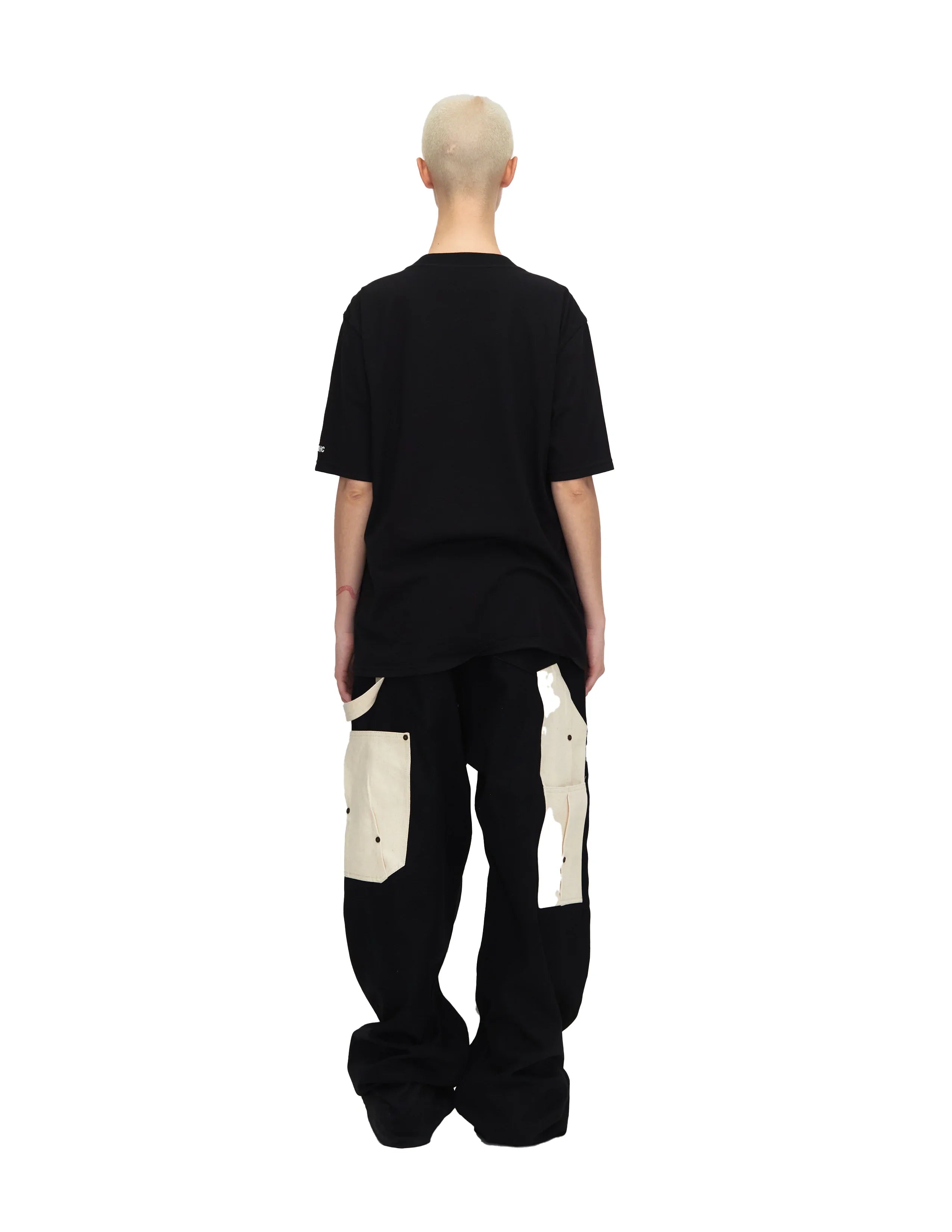 Back view of person wearing black oversized t-shirt and black pants with large white patch pockets