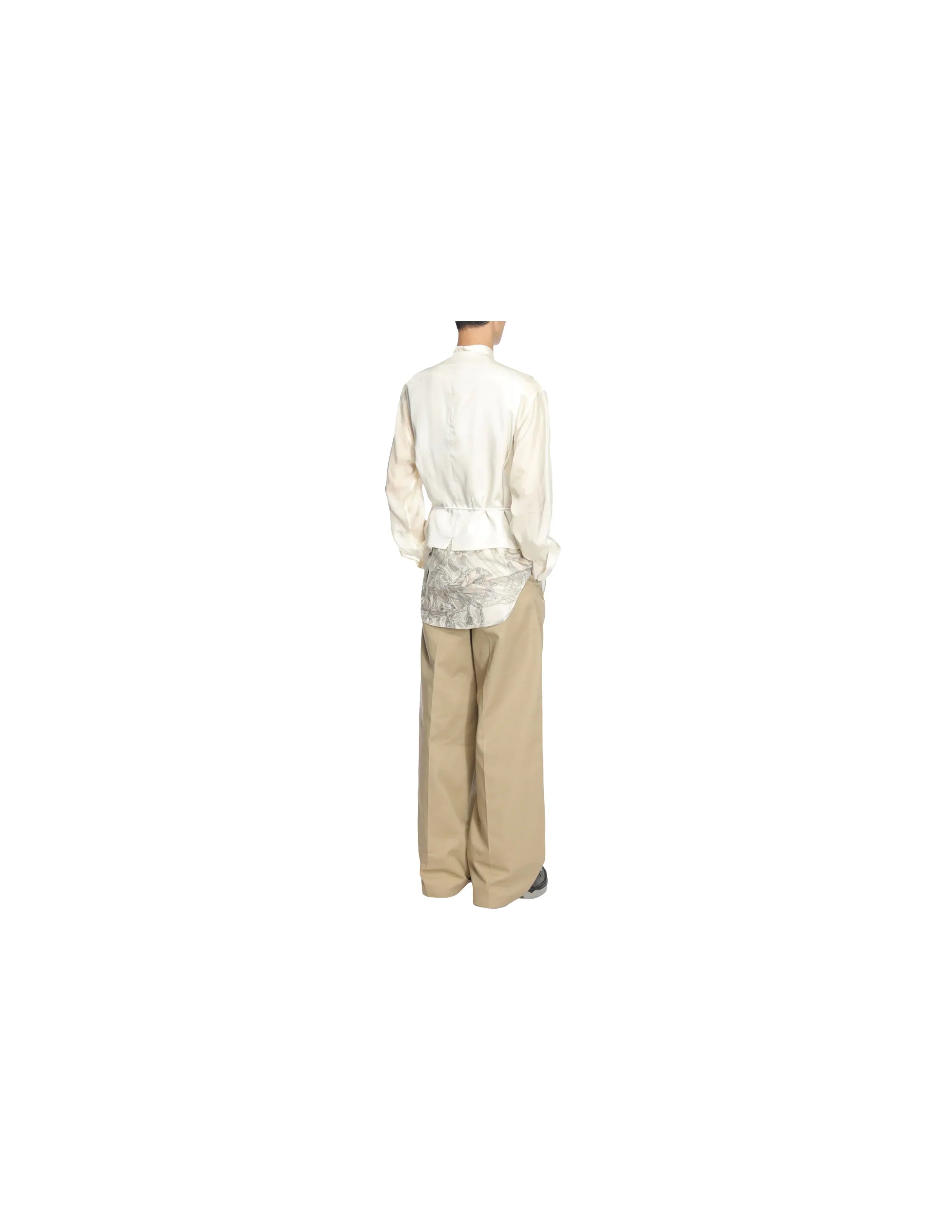 Rear view of person wearing cream juggler vest, floral shirt, wide beige pants, and grey shoes