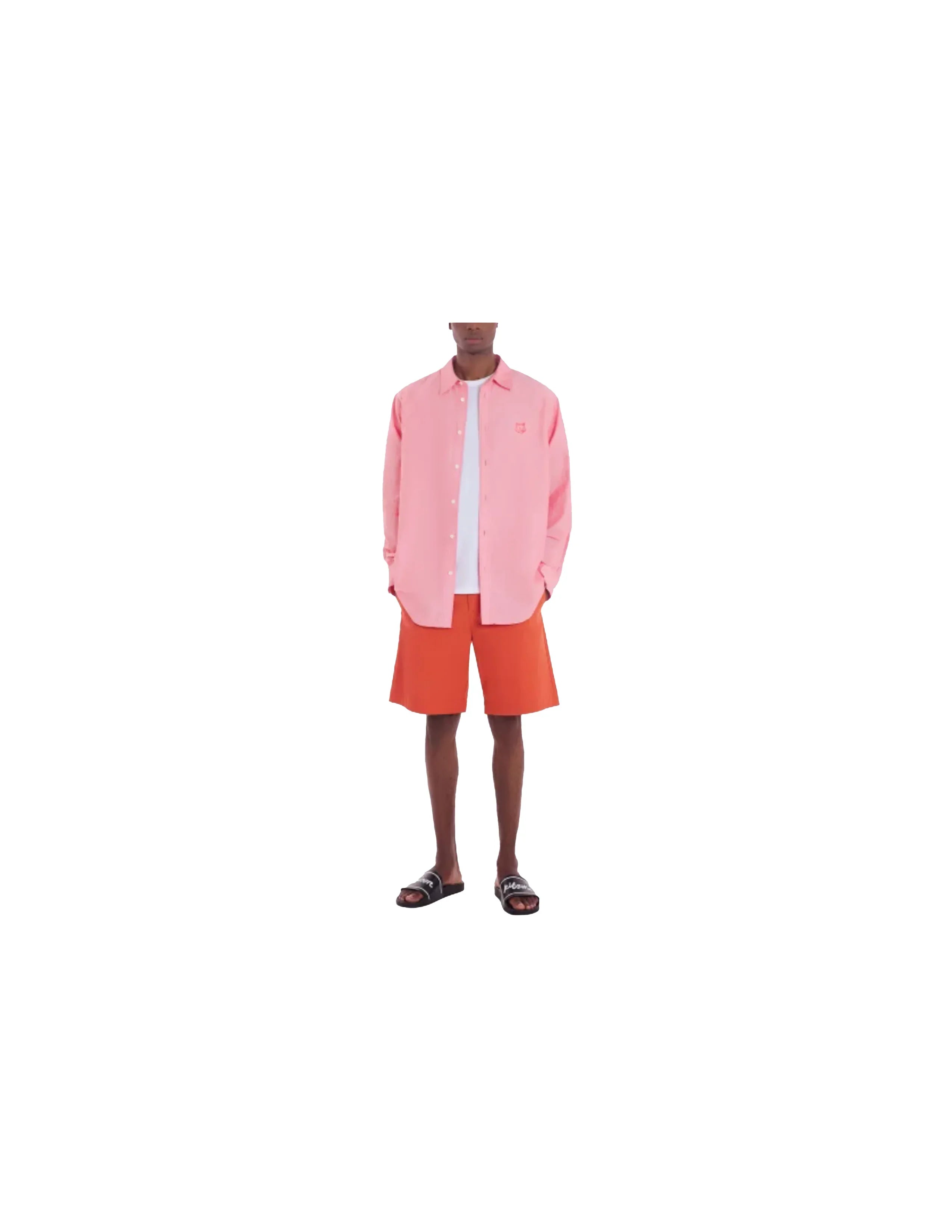 Man wearing pink button-up shirt, white t-shirt, orange shorts, and black slides against white background