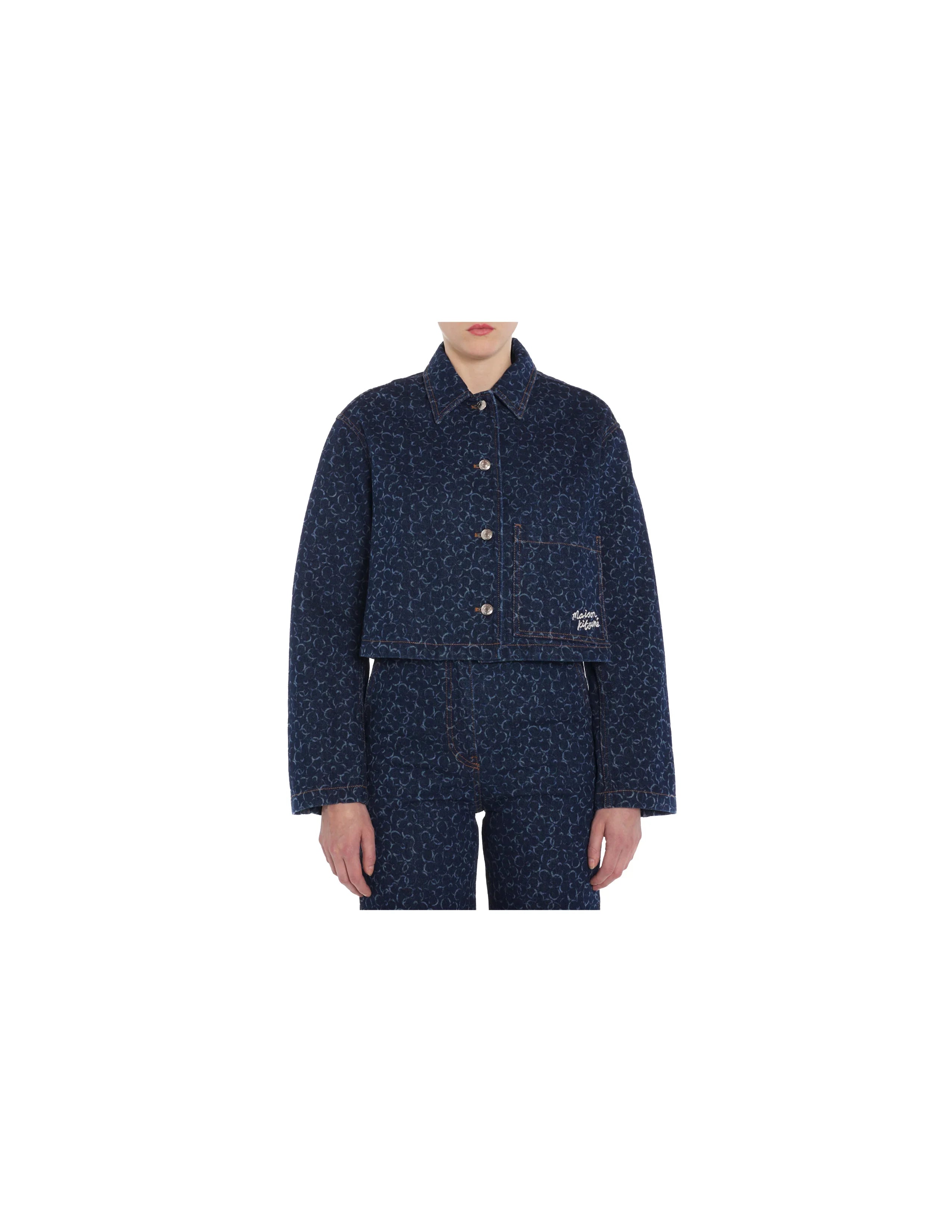 Front view of person wearing cropped navy denim jacket and matching pants with all-over embossed pattern