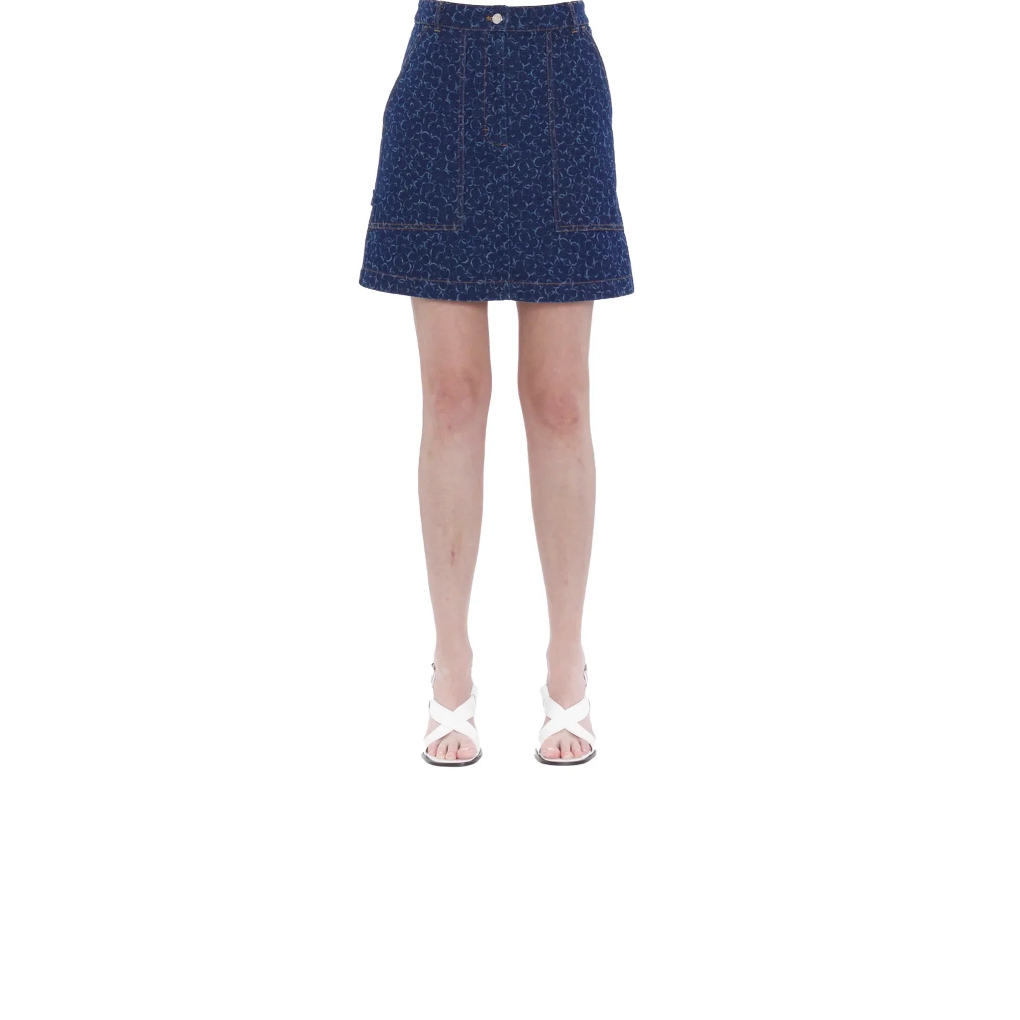 woman wearing mini denim skirt with subtle pattern and white heeled sandals on white background