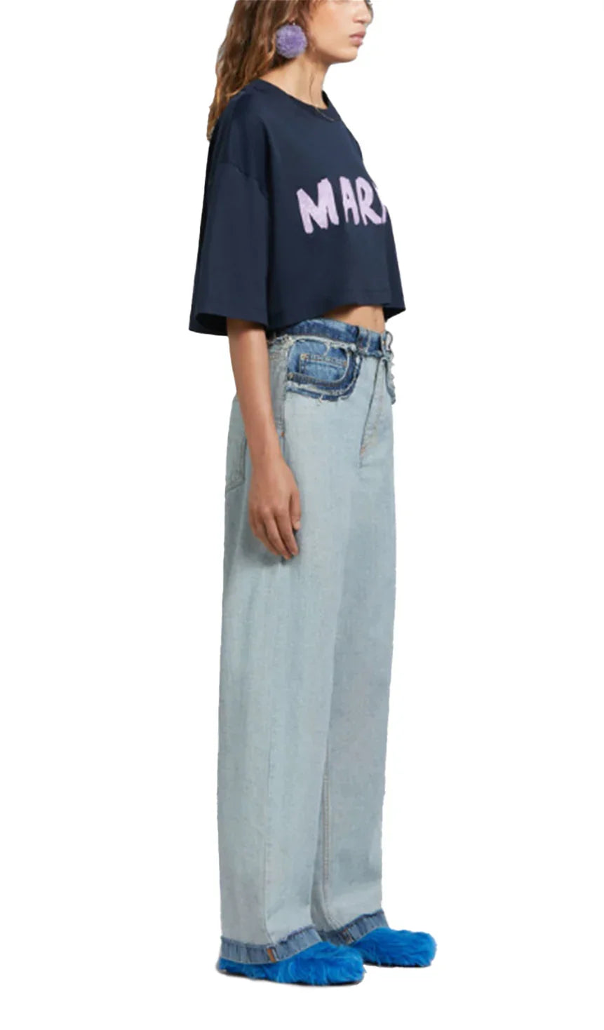 Side view of woman in cropped navy MARNIT t-shirt, high-waisted light wide-leg jeans, and blue fuzzy slippers