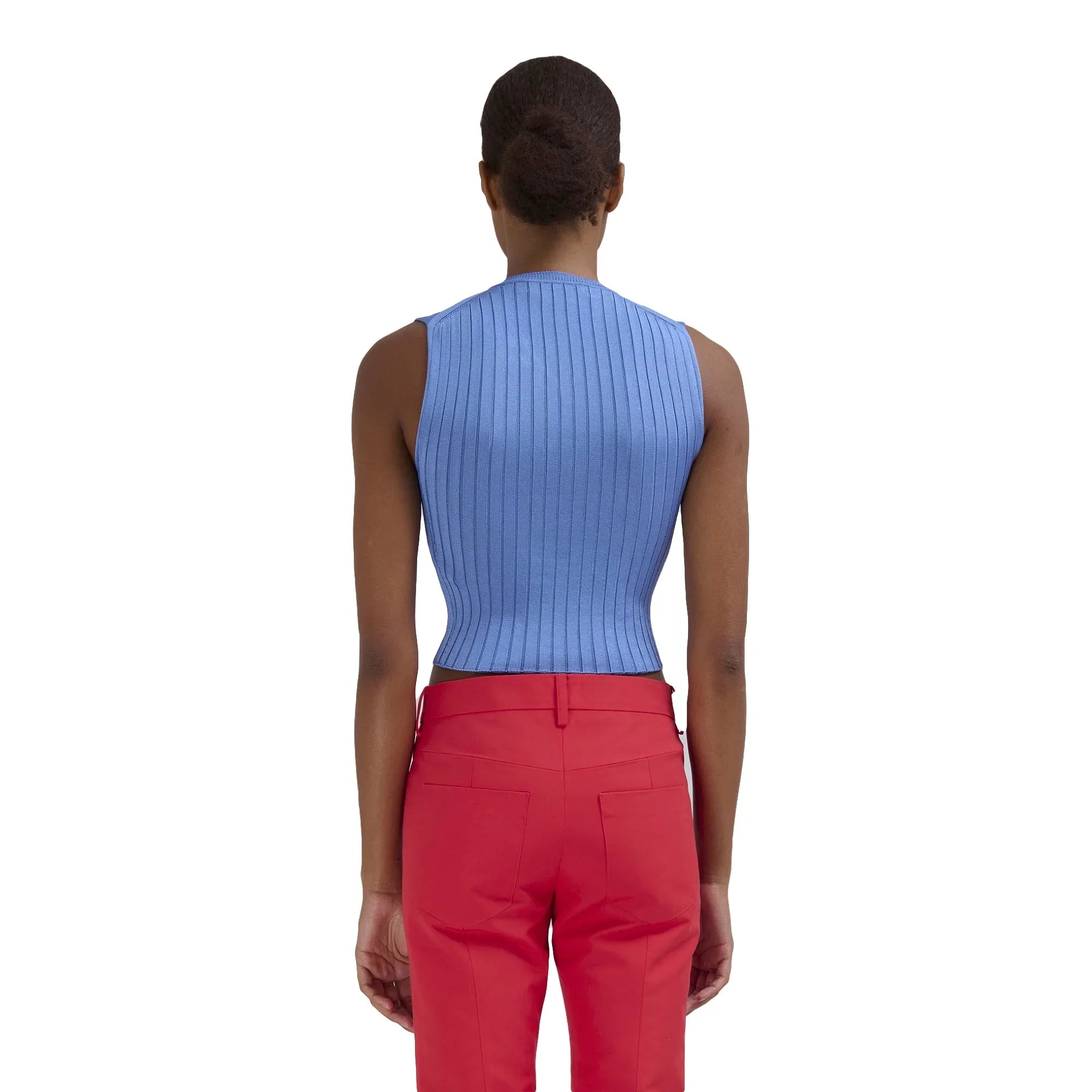 Back view of woman wearing blue ribbed sleeveless top and red pants on white background