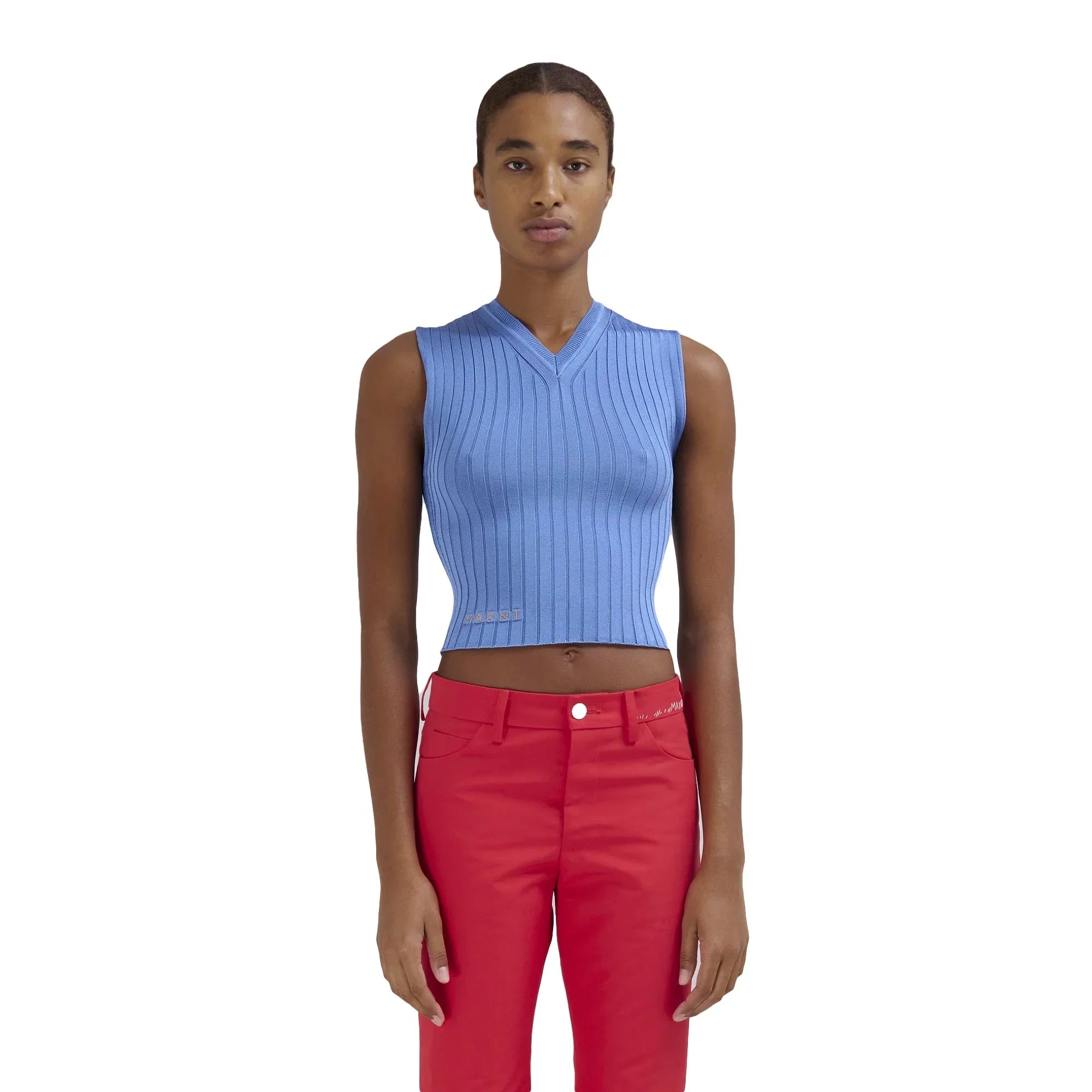 Model wearing sleeveless ribbed blue crop top and red pants on white background