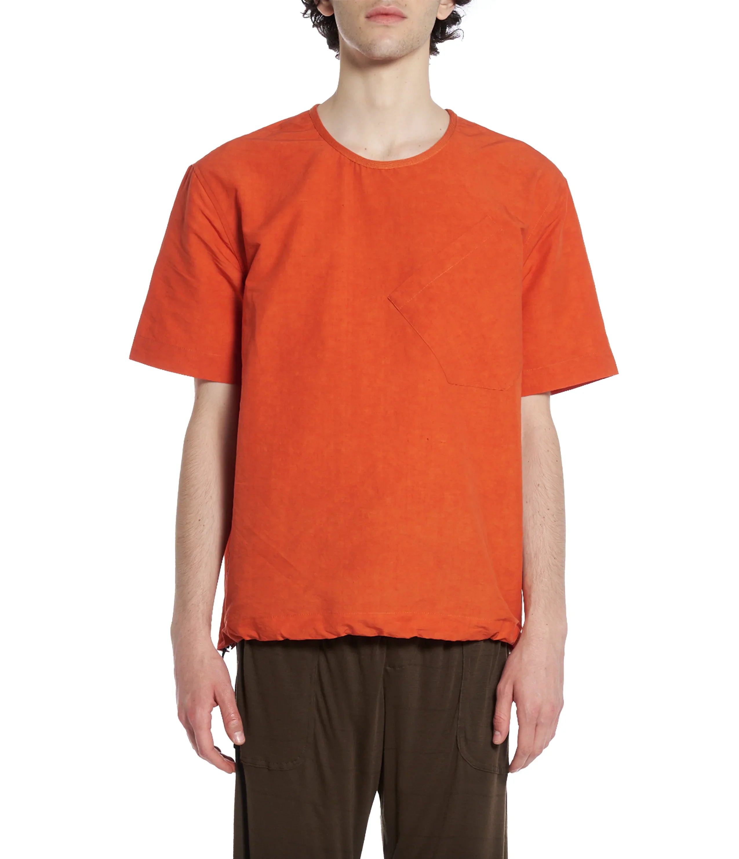 Man wearing a plain orange short-sleeve pocket T-shirt with dark brown pants