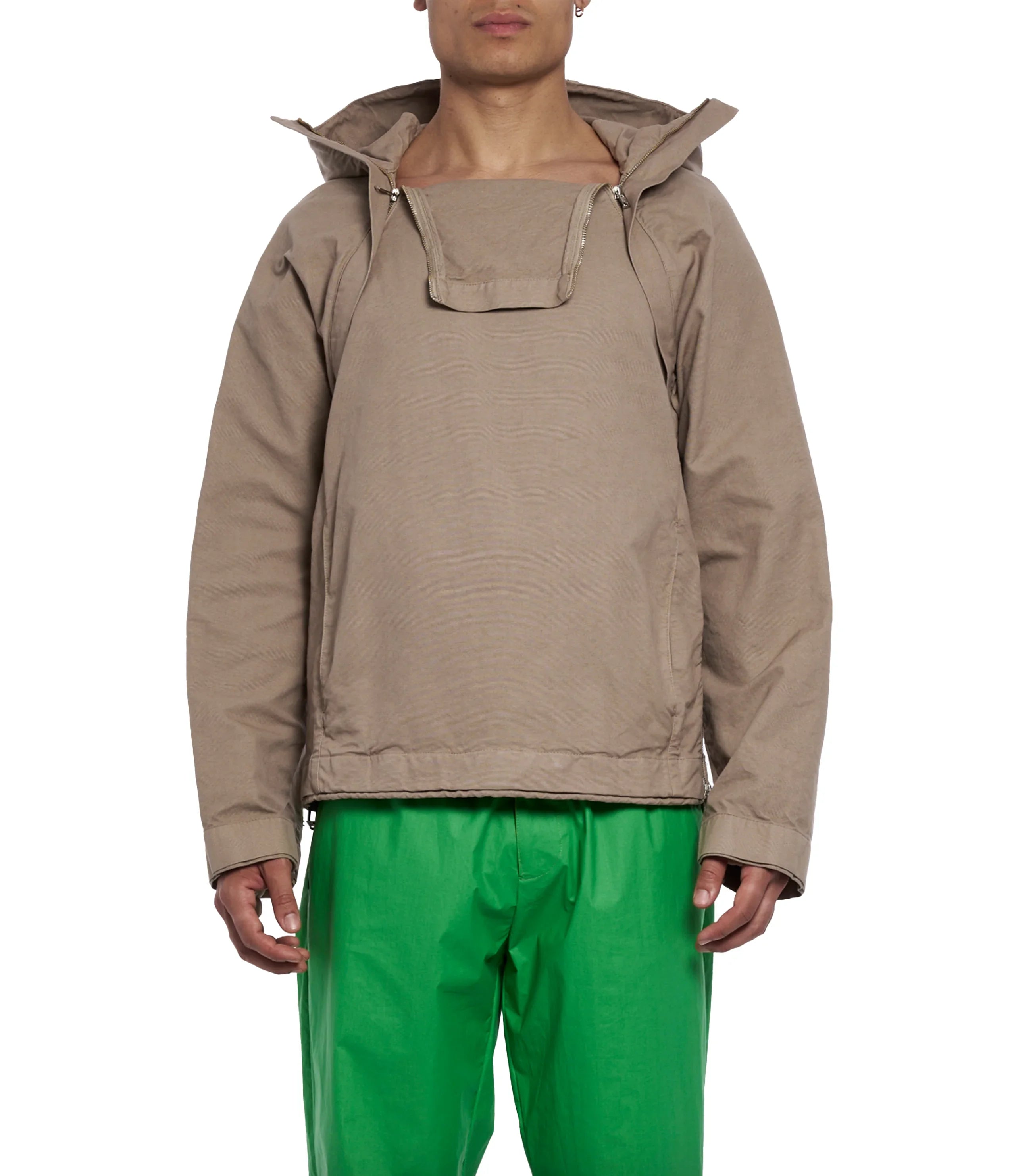 Man wearing a beige hooded jacket with zipper detail and bright green pants on white background
