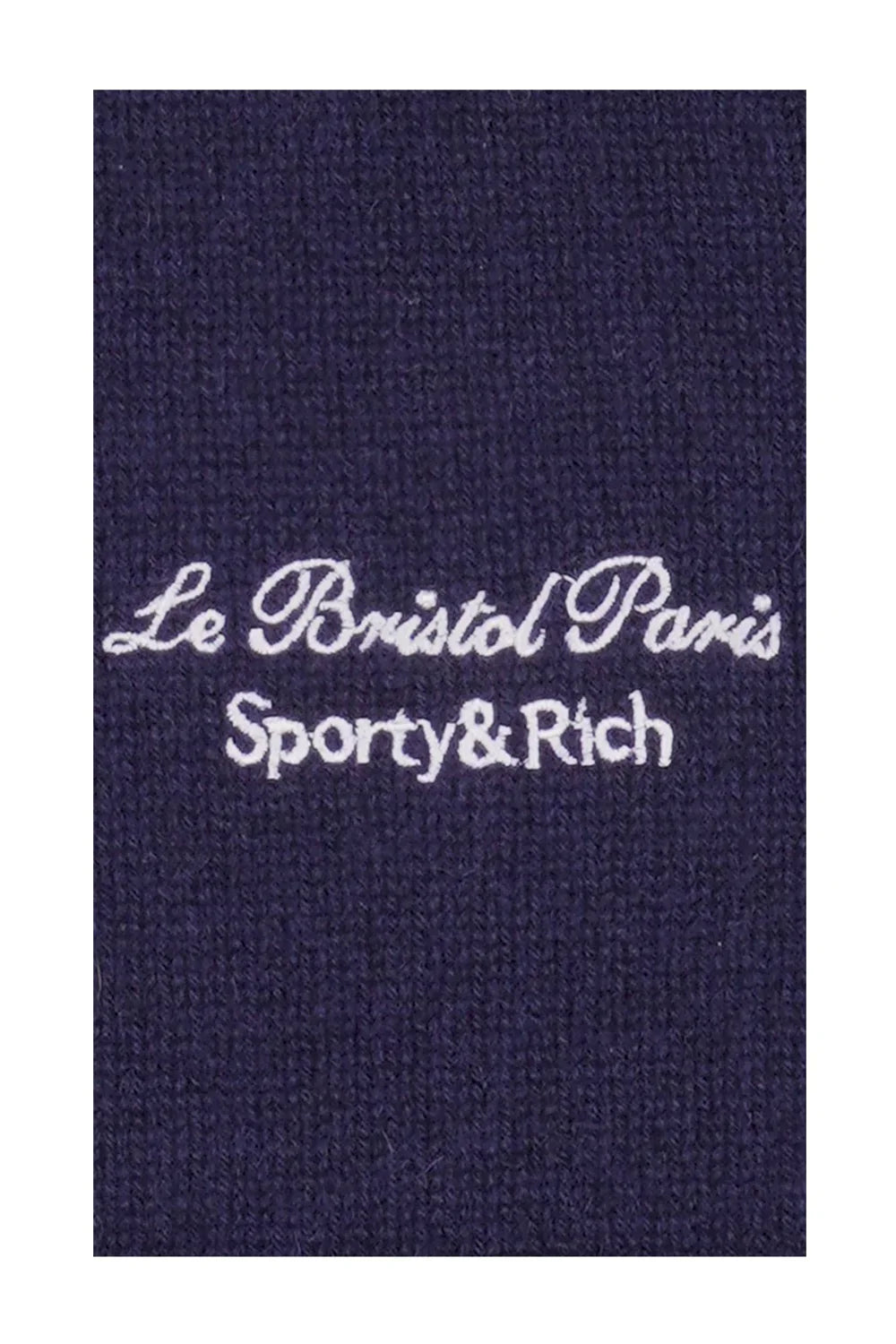 Close-up of navy blue knit fabric with white embroidery reading Le Bristol Paris Sporty & Rich