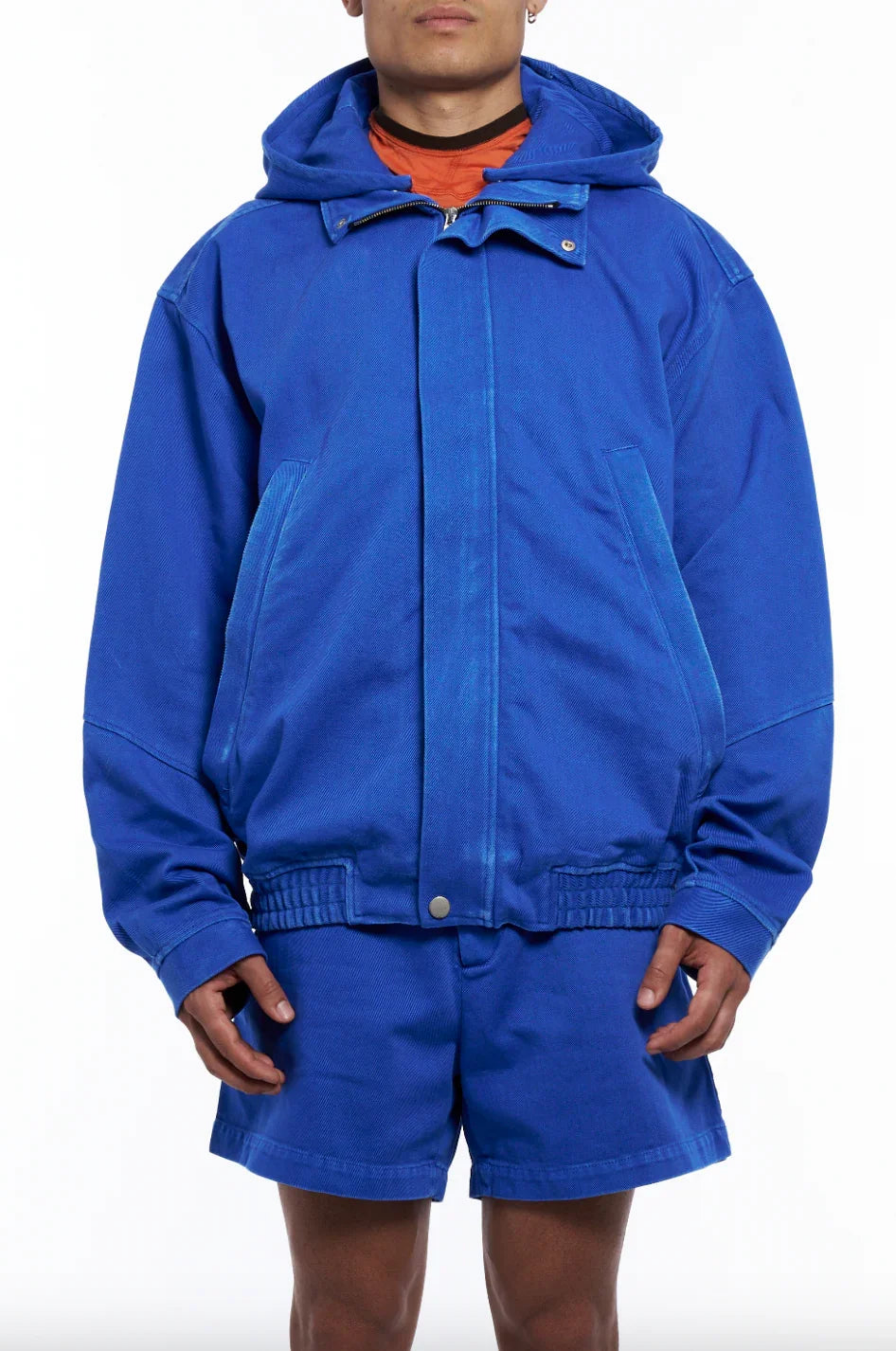 Man wearing bright blue hooded jacket and matching blue shorts with visible pockets