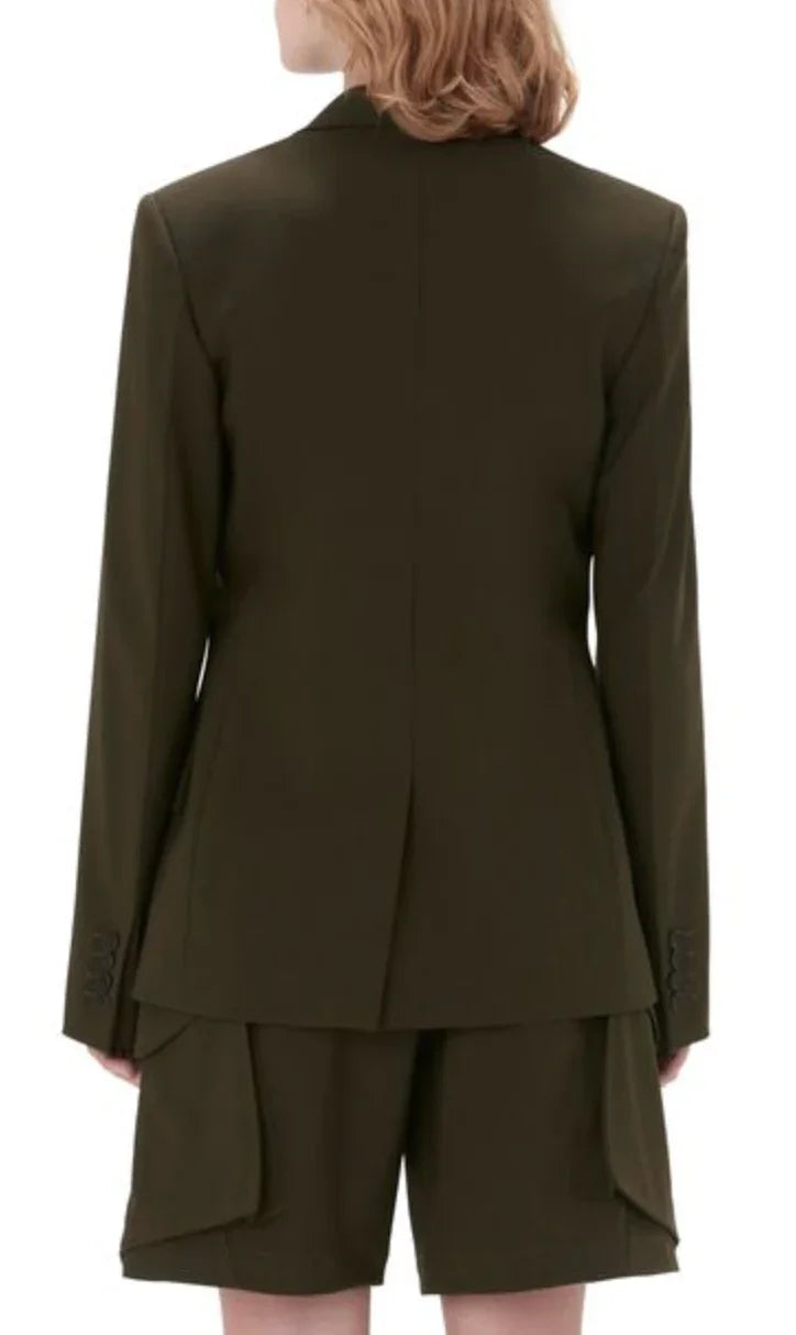 Back view of a woman wearing an olive green tailored blazer and matching shorts with flap pockets